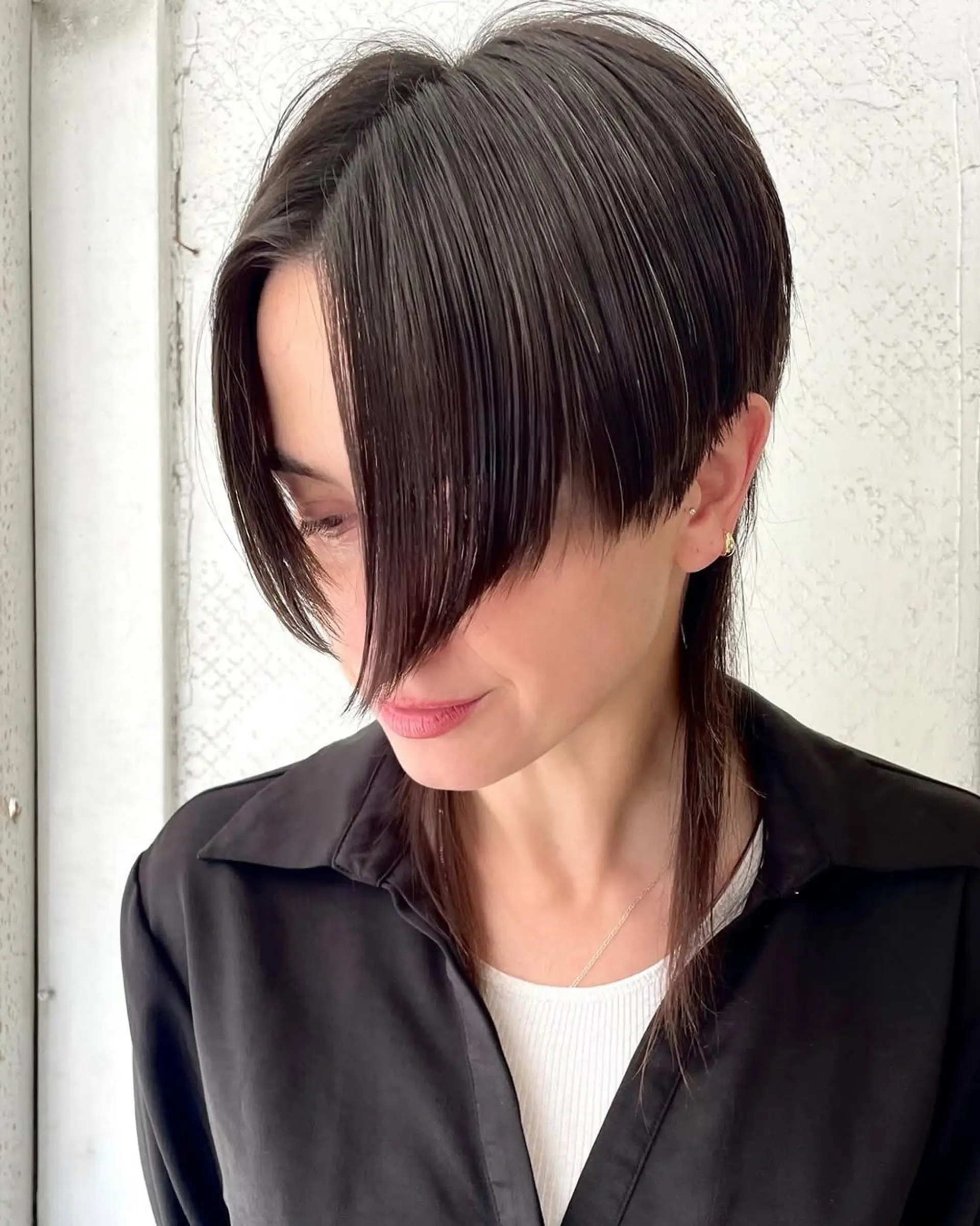 A sleek, asymmetrical layered bob with a deep side fringe, featuring neck-length dark brown straight hair. 2