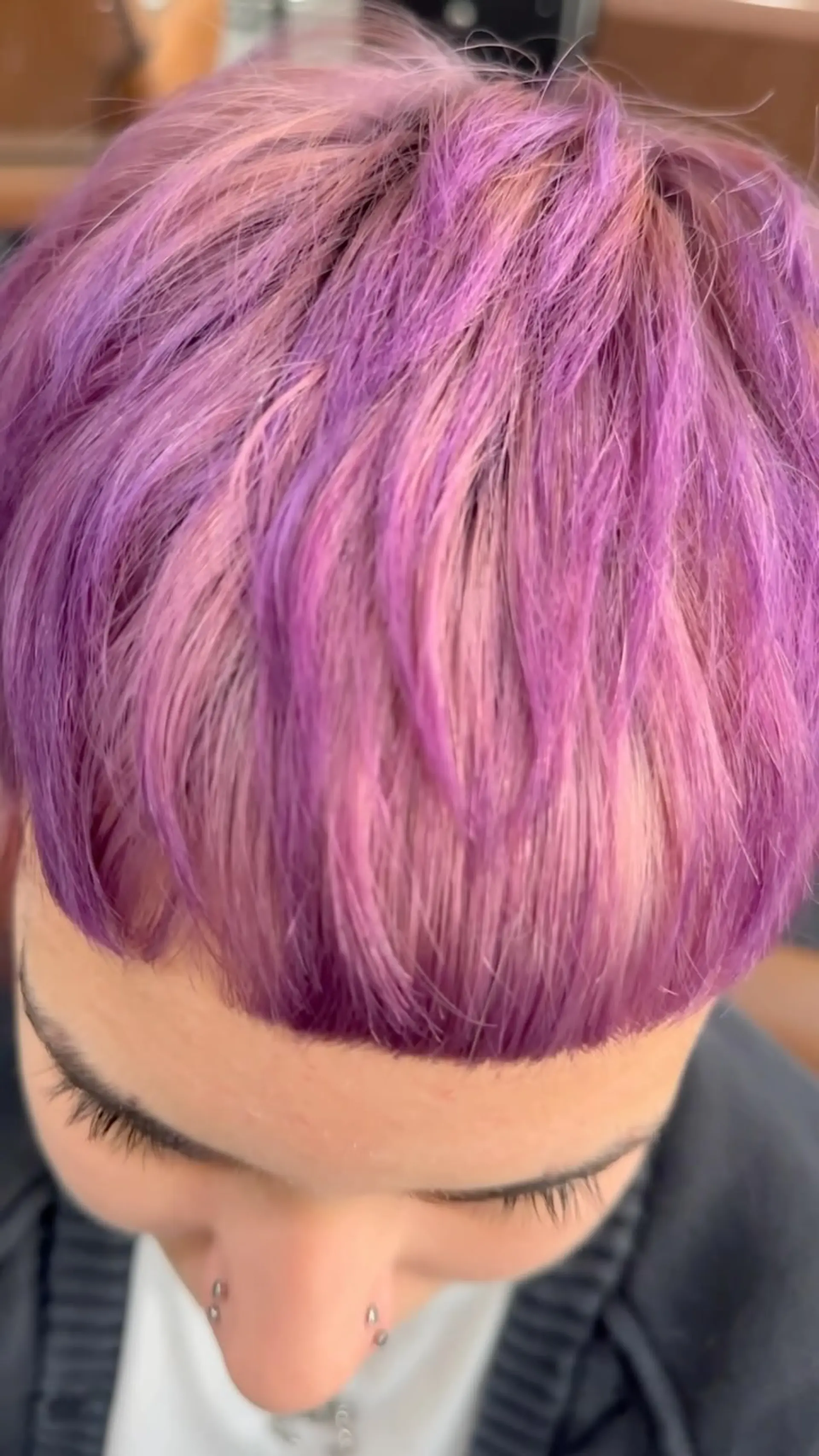 A short textured crop featuring blunt micro bangs and multi-tonal shades of vibrant purple, lavender, and soft pink. 1
