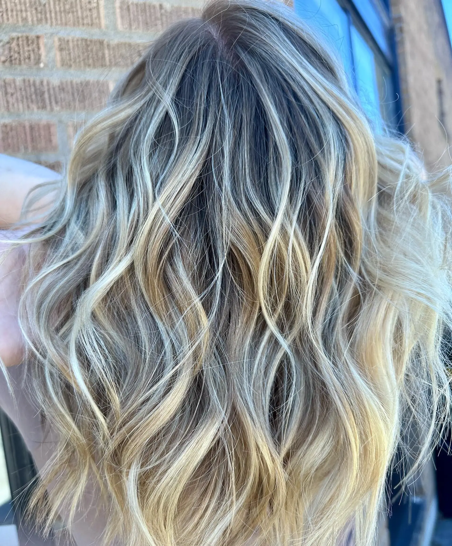 Medium-length textured hair with dimensional blonde balayage styled in loose, lived-in waves. 1