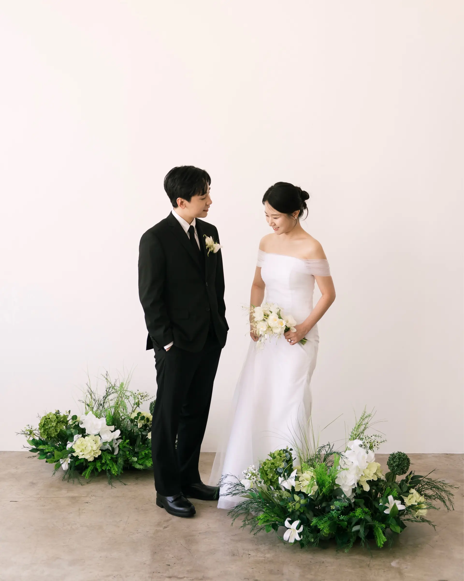 A romantic bridal low bun paired with a cleanly styled classic groom haircut for a studio wedding shoot. 1