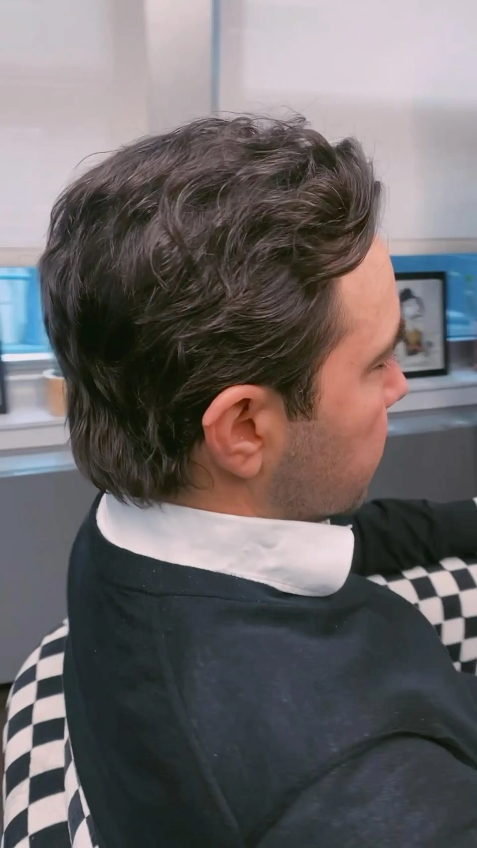 A modern wavy mullet featuring shorter, tapered sides blended into soft, textured layers with length extending down the nape. 1