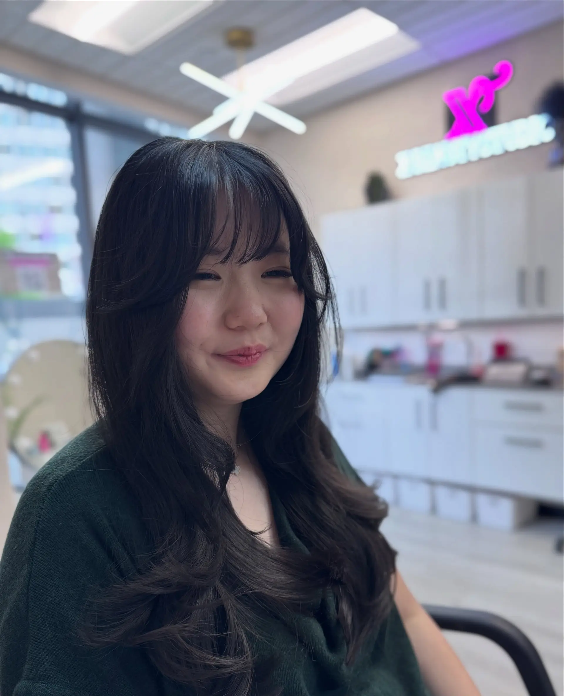Long dark layered haircut featuring airy, wispy bangs and voluminous face-framing layers styled in soft waves. 1