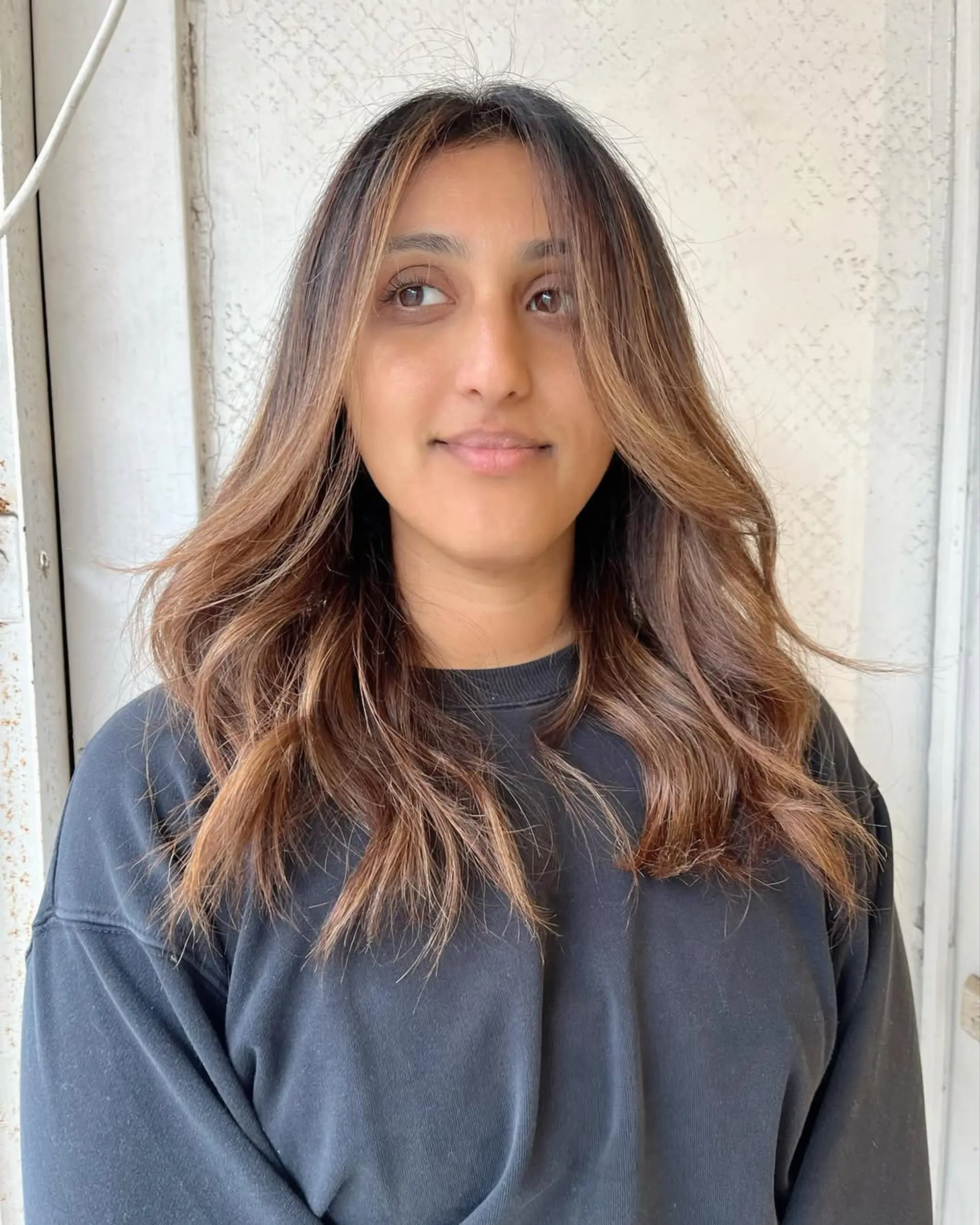 Long, wavy hair with dark brown to honey blonde and caramel highlights, featuring soft waves and textured layers for natural flow and warmth. 2