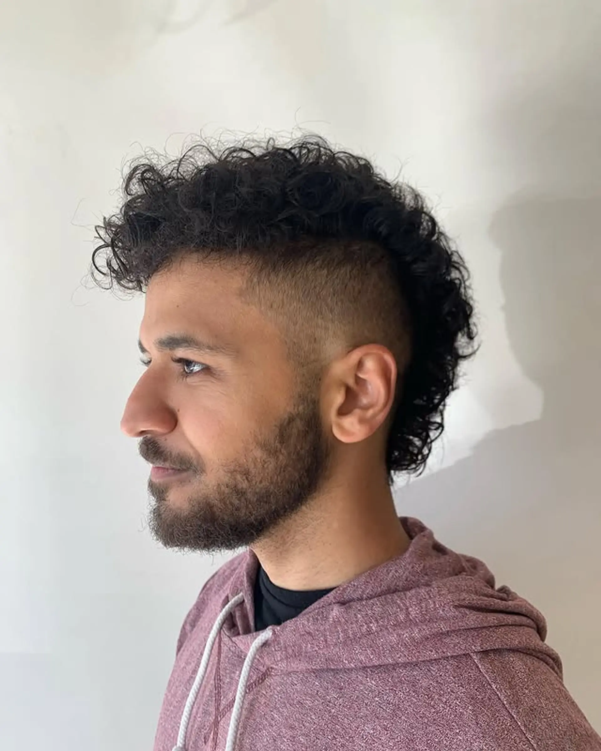 This hairstyle is a short, curly mohawk with a fade on the sides. 1