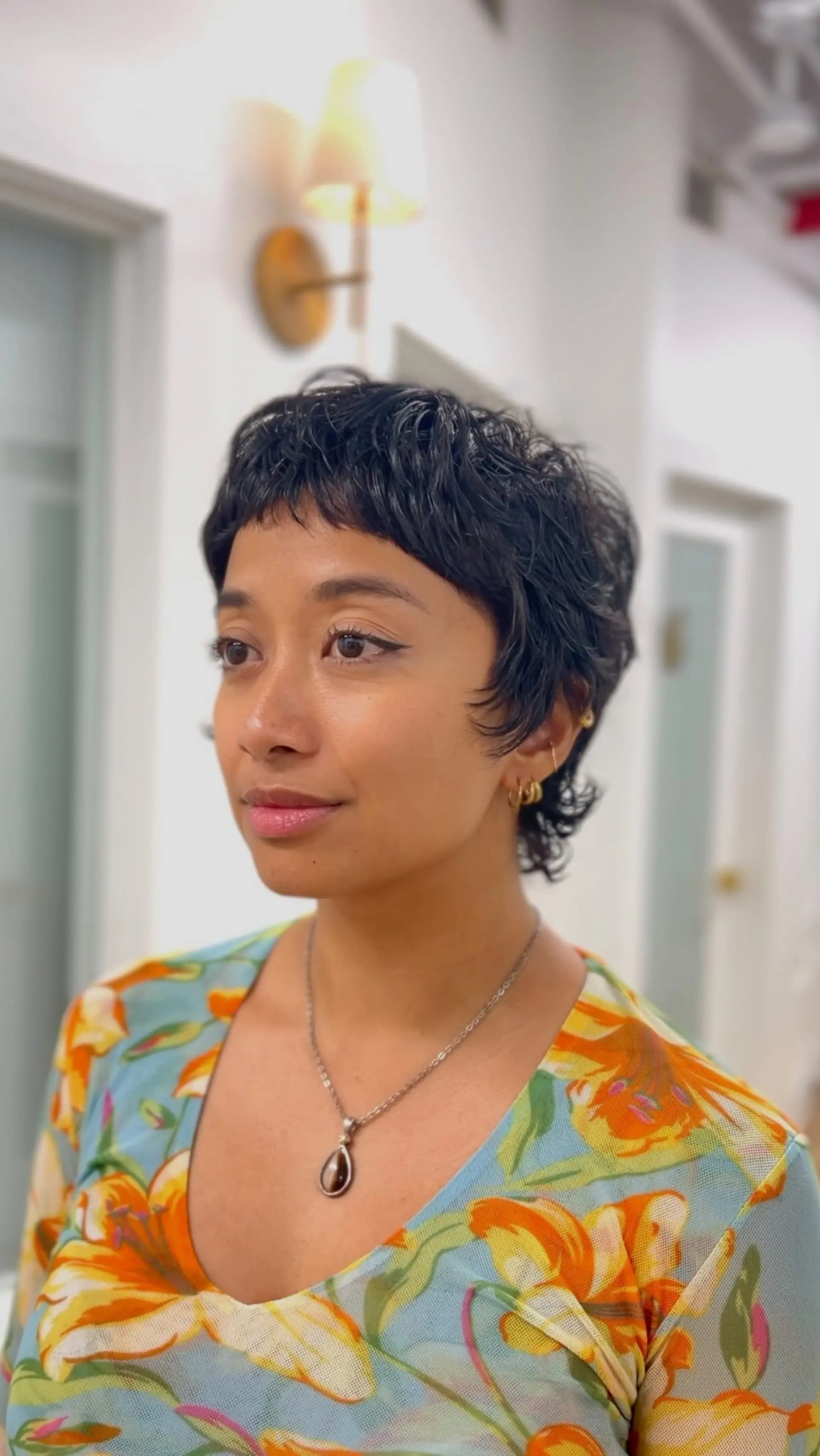 A short, wavy pixie mullet with piecey micro bangs and textured layers throughout. 1