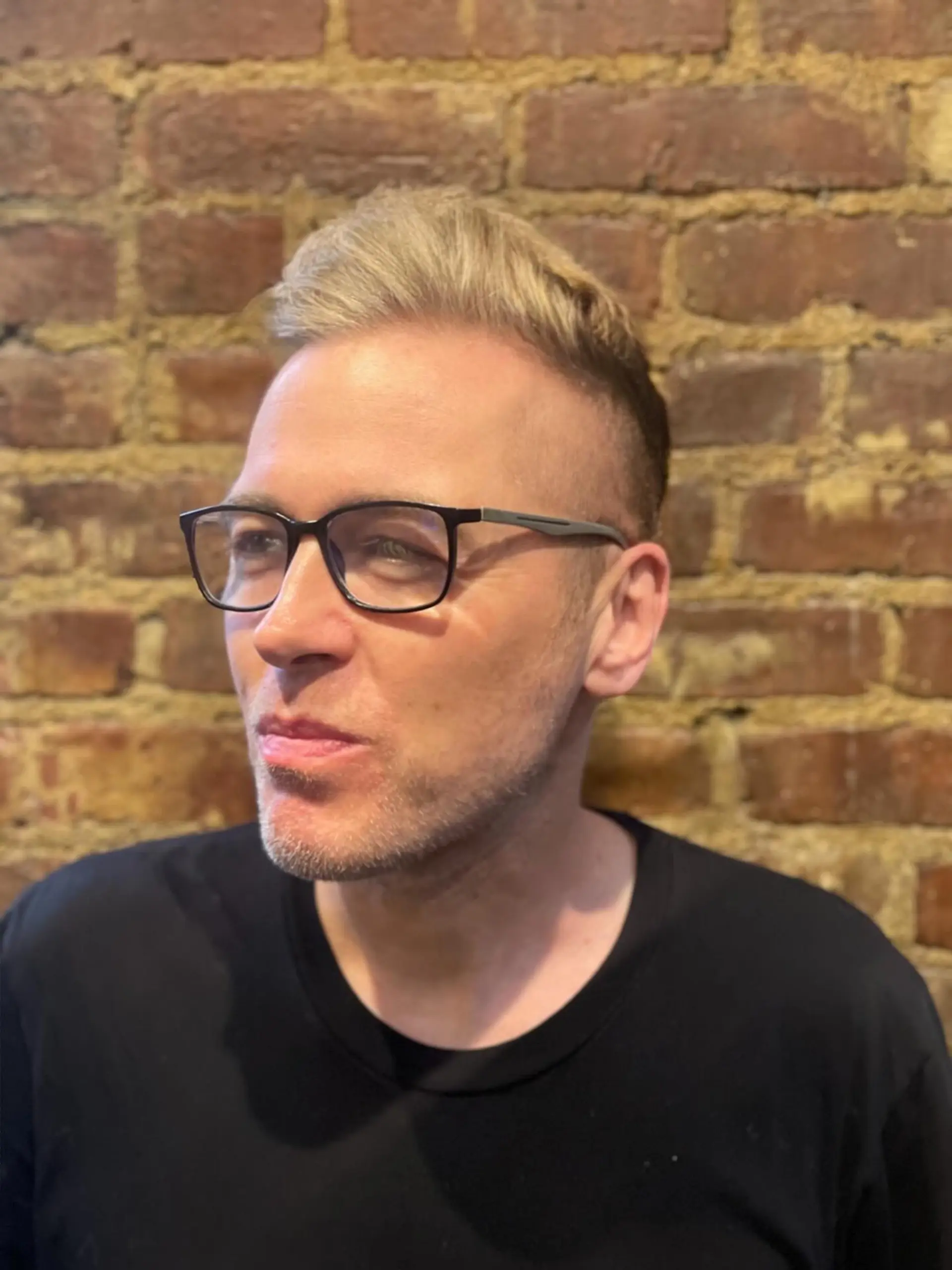 A men's short haircut featuring closely faded sides with textured, swept-up blonde length on top. Current Cut My Hair service: $215 for haircut and included finish only; displayed color is not included. 1