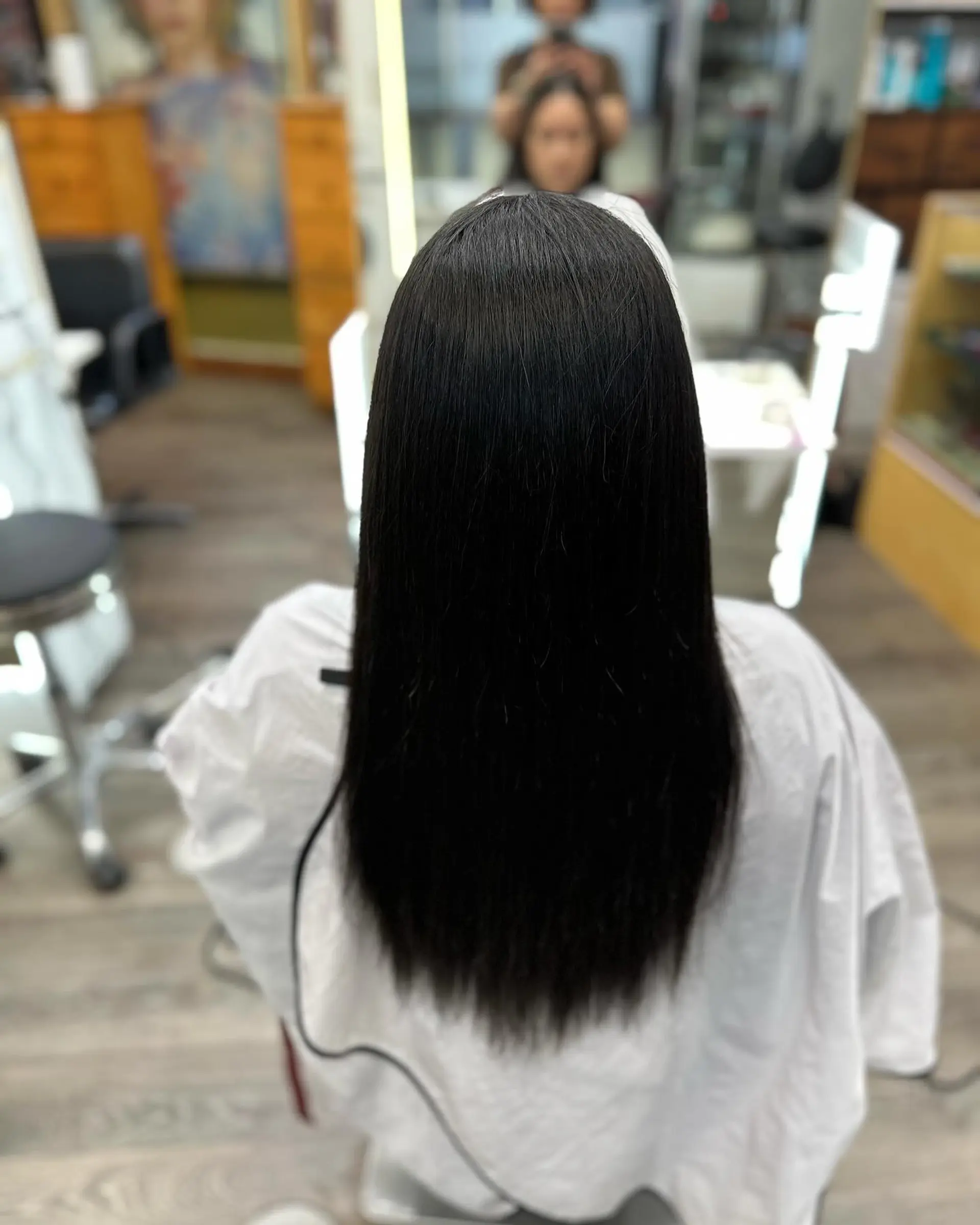 Sleek, glossy straight dark hair falling down the center of the back. 1