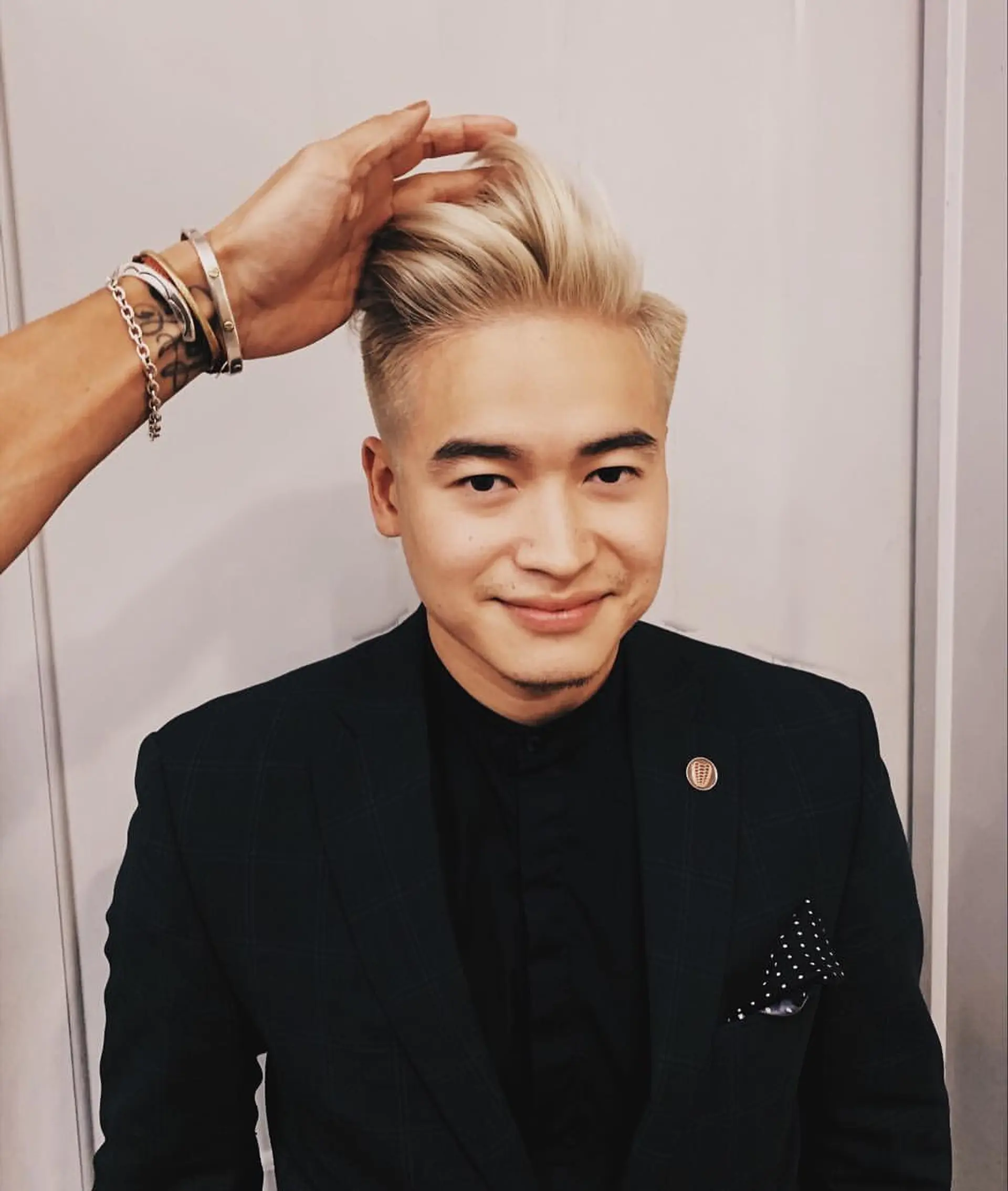 A sleek, high-volume pompadour with platinum blonde highlights, featuring a smooth, side-swept top and neatly trimmed sides. 1