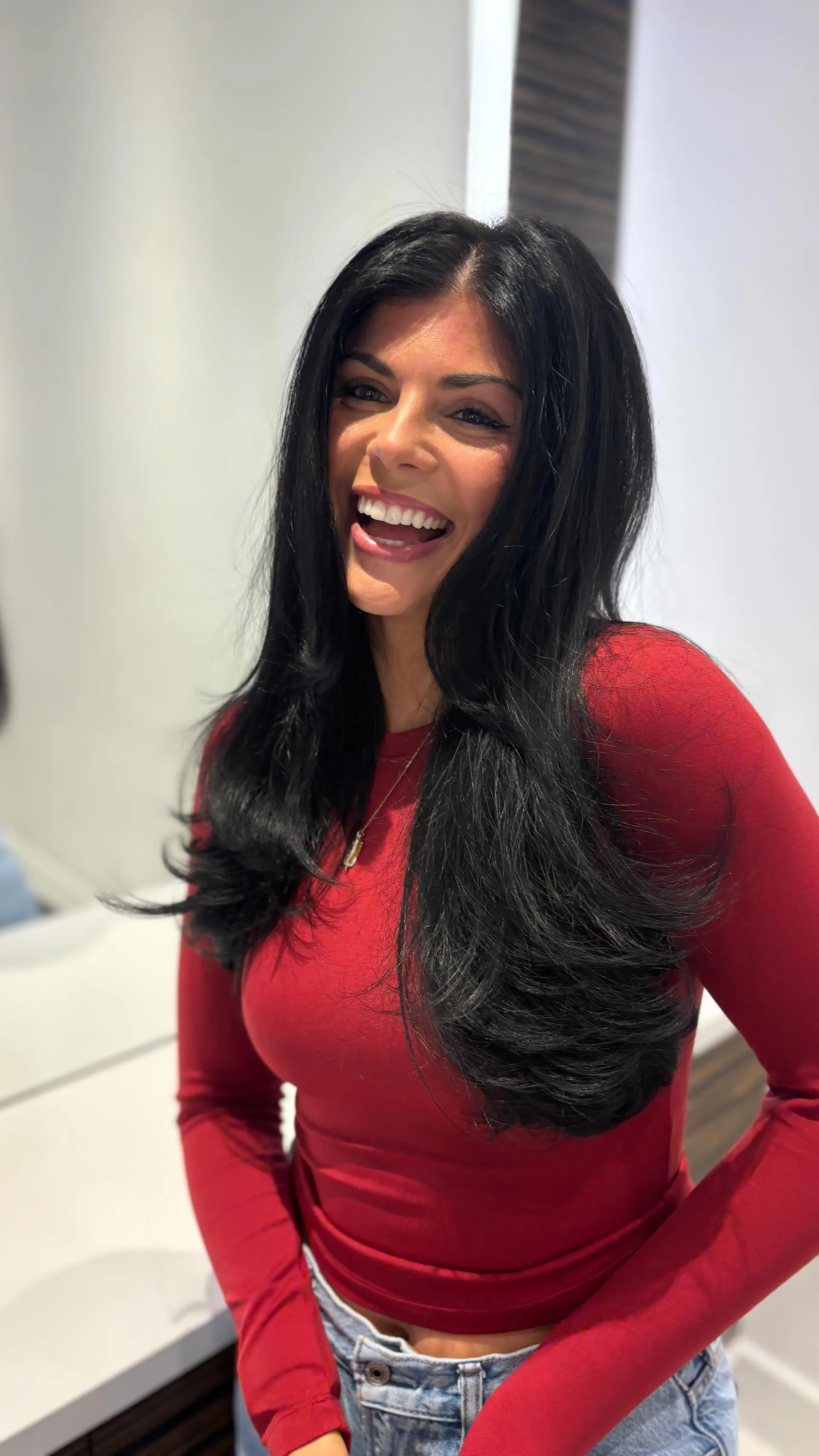 Long, glossy jet-black hair styled in a bouncy, voluminous blowout with flipped layered ends. 1