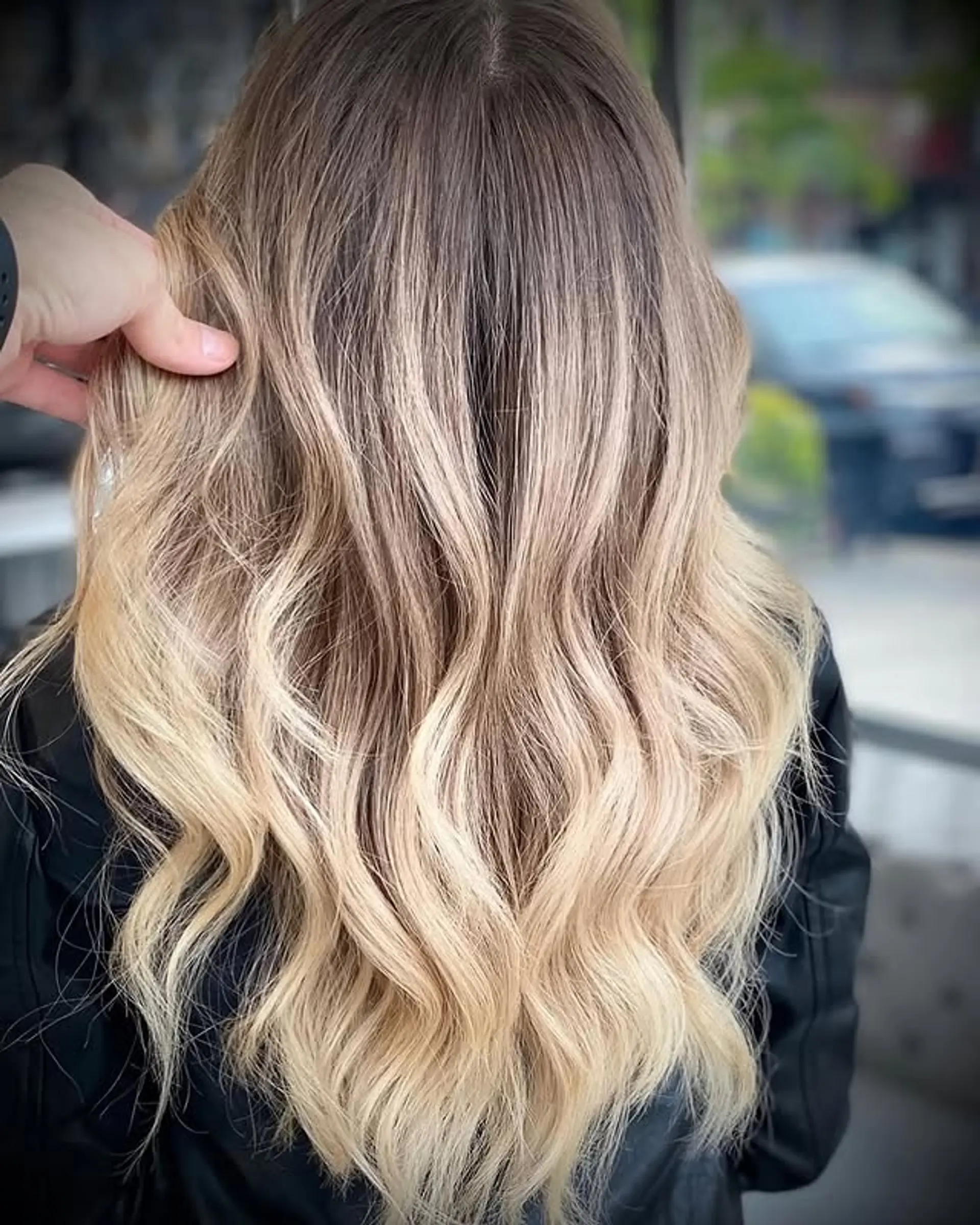 Long, wavy hairstyle with a blonde balayage and dark roots, styled in beachy waves. 1