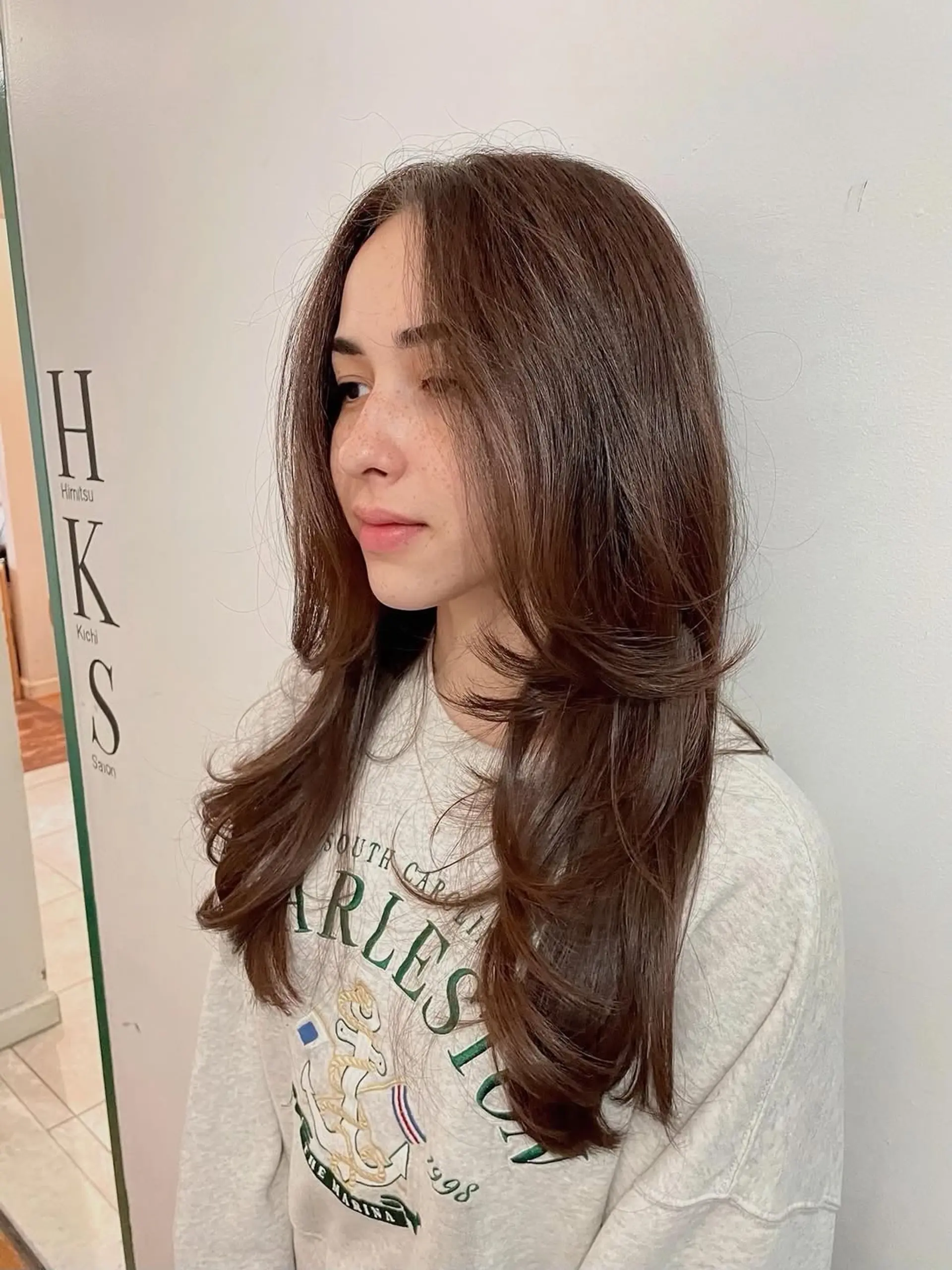 This long haircut features a dramatic layered style, often called a butterfly cut, with face-framing layers that are feathered to create maximum volume and a soft, airy feel. The ends are styled with a gentle curl to enhance the voluminous silhouette. 1