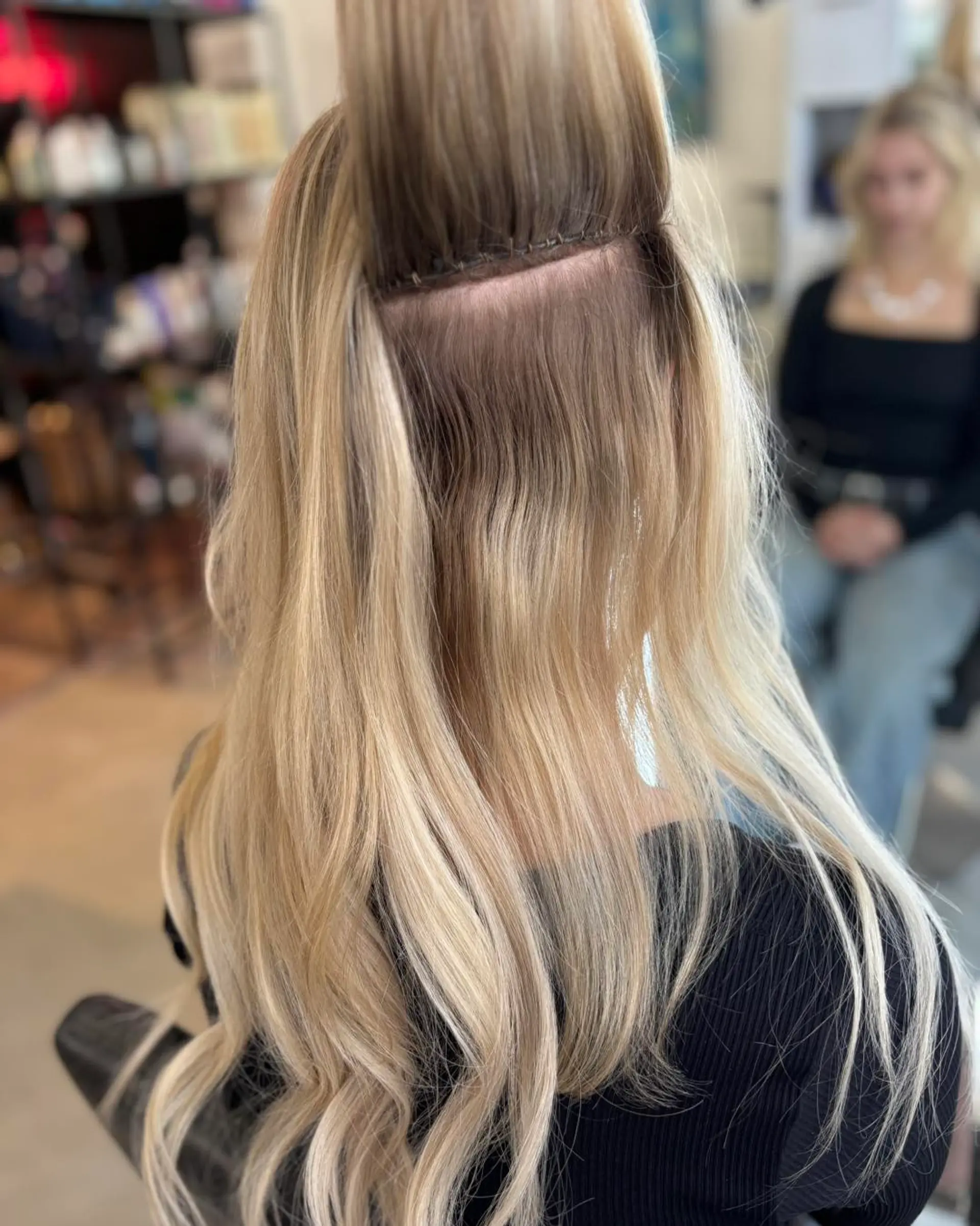Dimensional blonde hair showcasing a clean sew-in weft extension installation with soft waves. 1