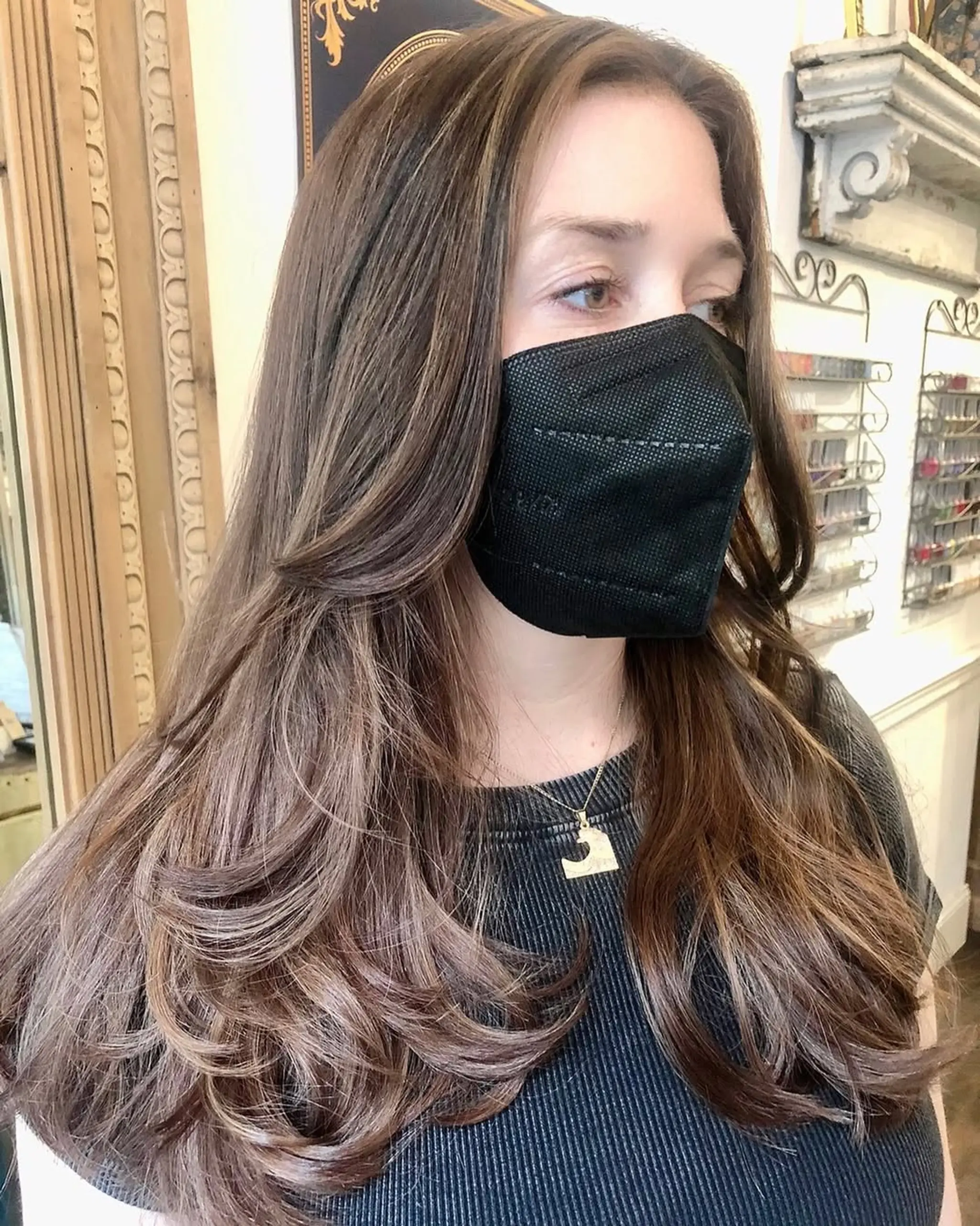 Long, light brown wavy hair with subtle highlights and soft waves. Natural volume with layered, face-framing ends.