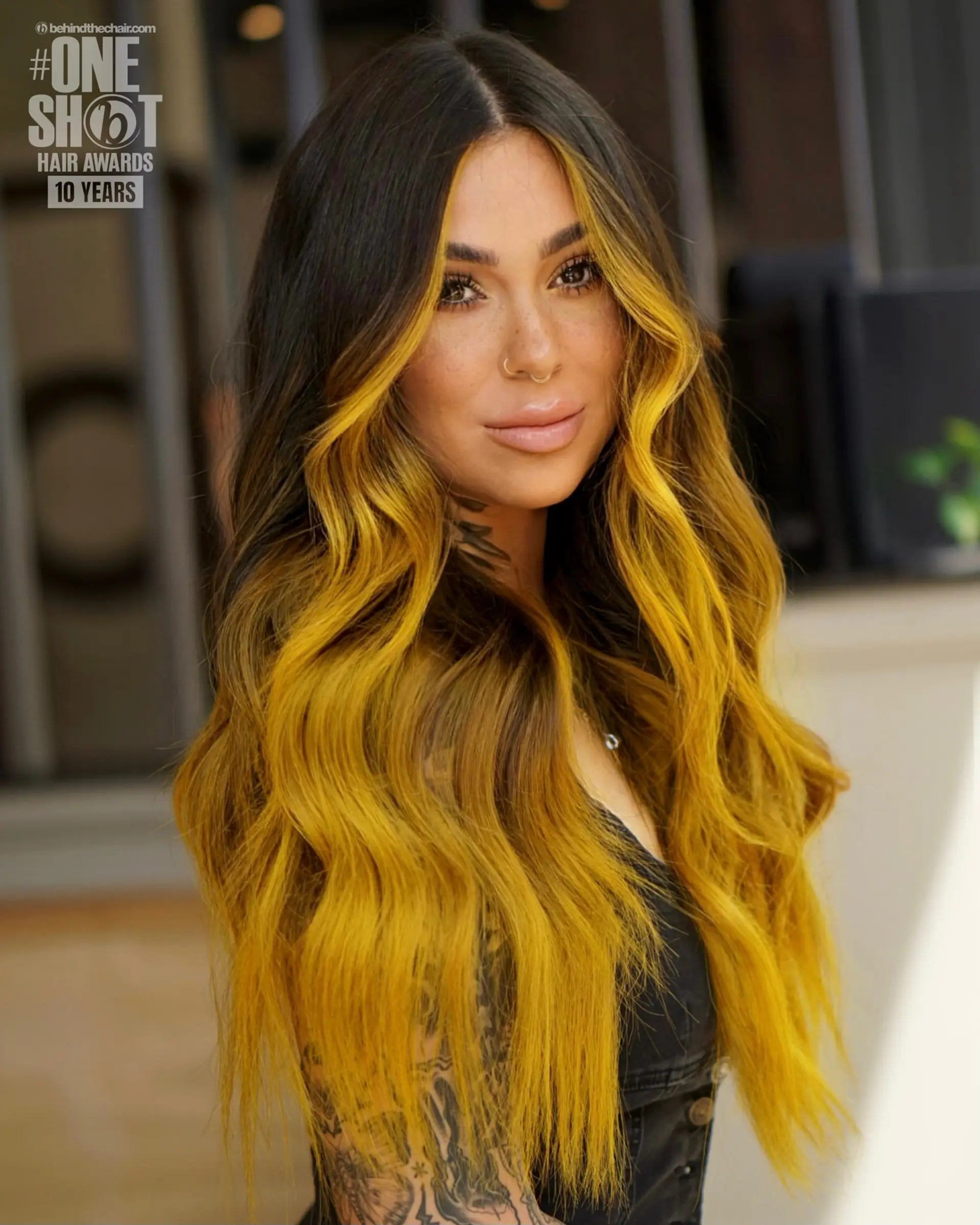 Long dark hair transitioning into a rich golden-yellow balayage with vivid face-framing money pieces, styled in soft dimensional waves. 1