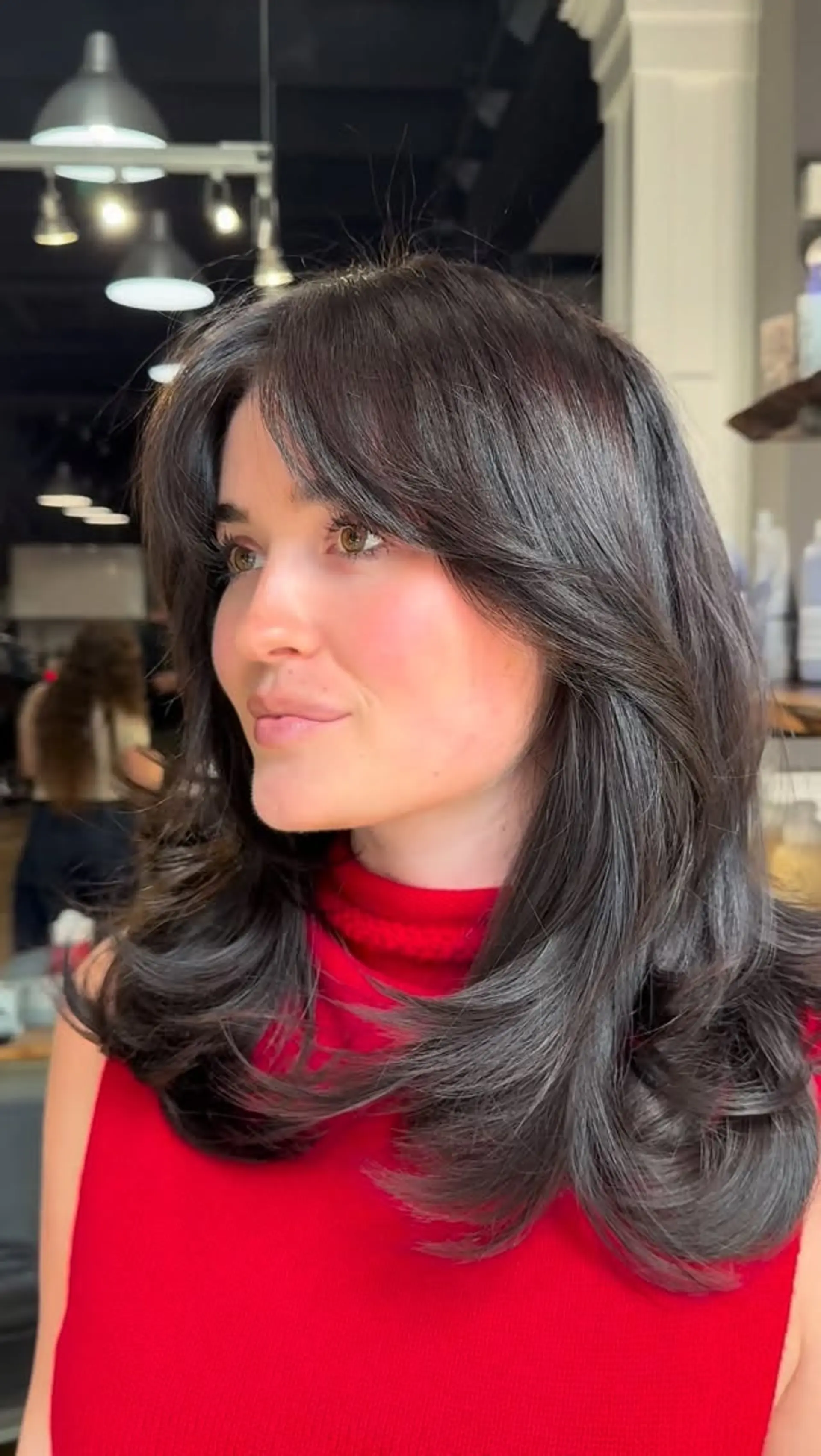 Medium-length dark brown hair featuring feathered curtain bangs and voluminous, flipped-in layers. 1