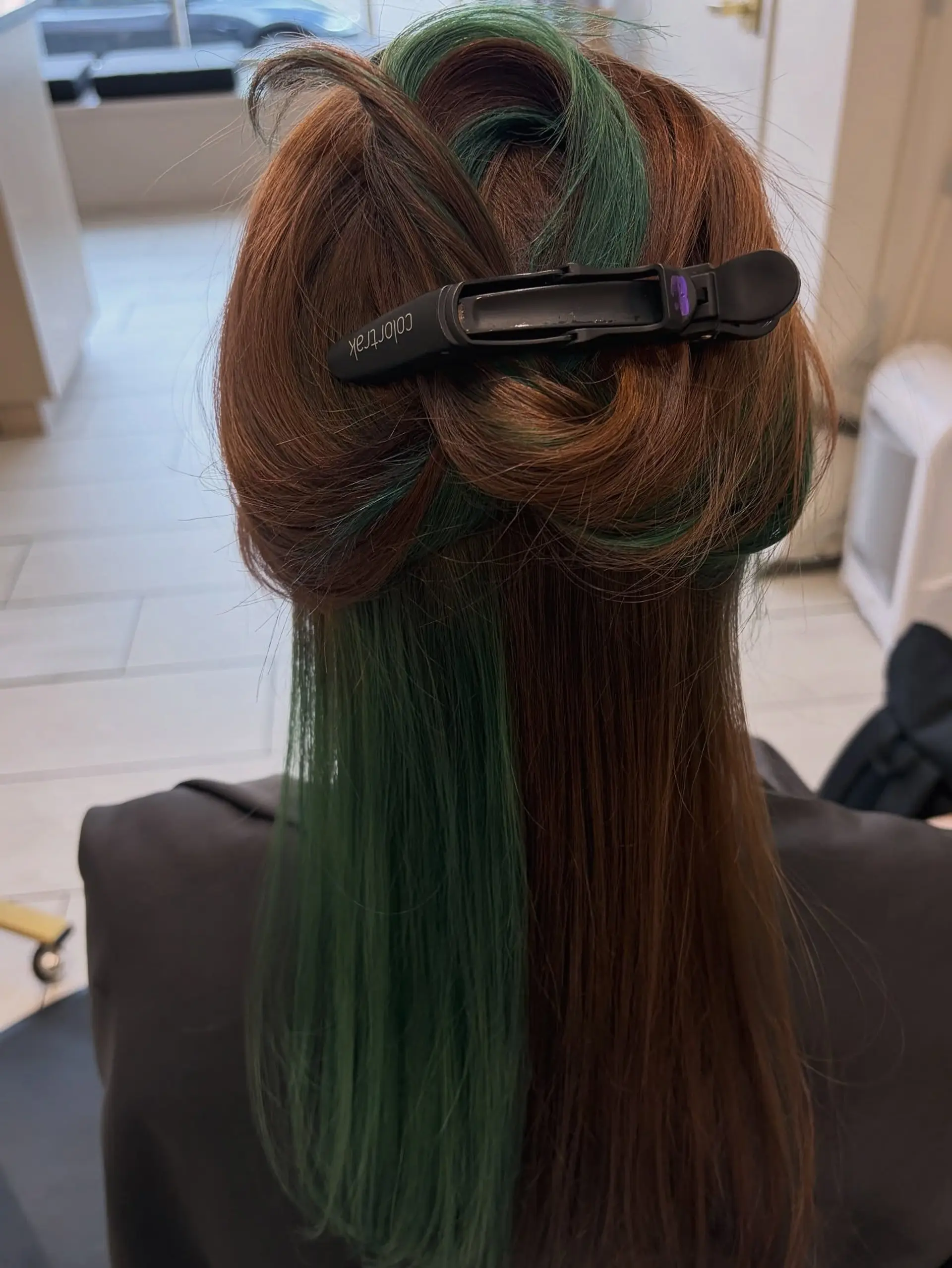 Straight long brown hair pinned up to showcase a vibrant emerald green peekaboo underlayer. 1