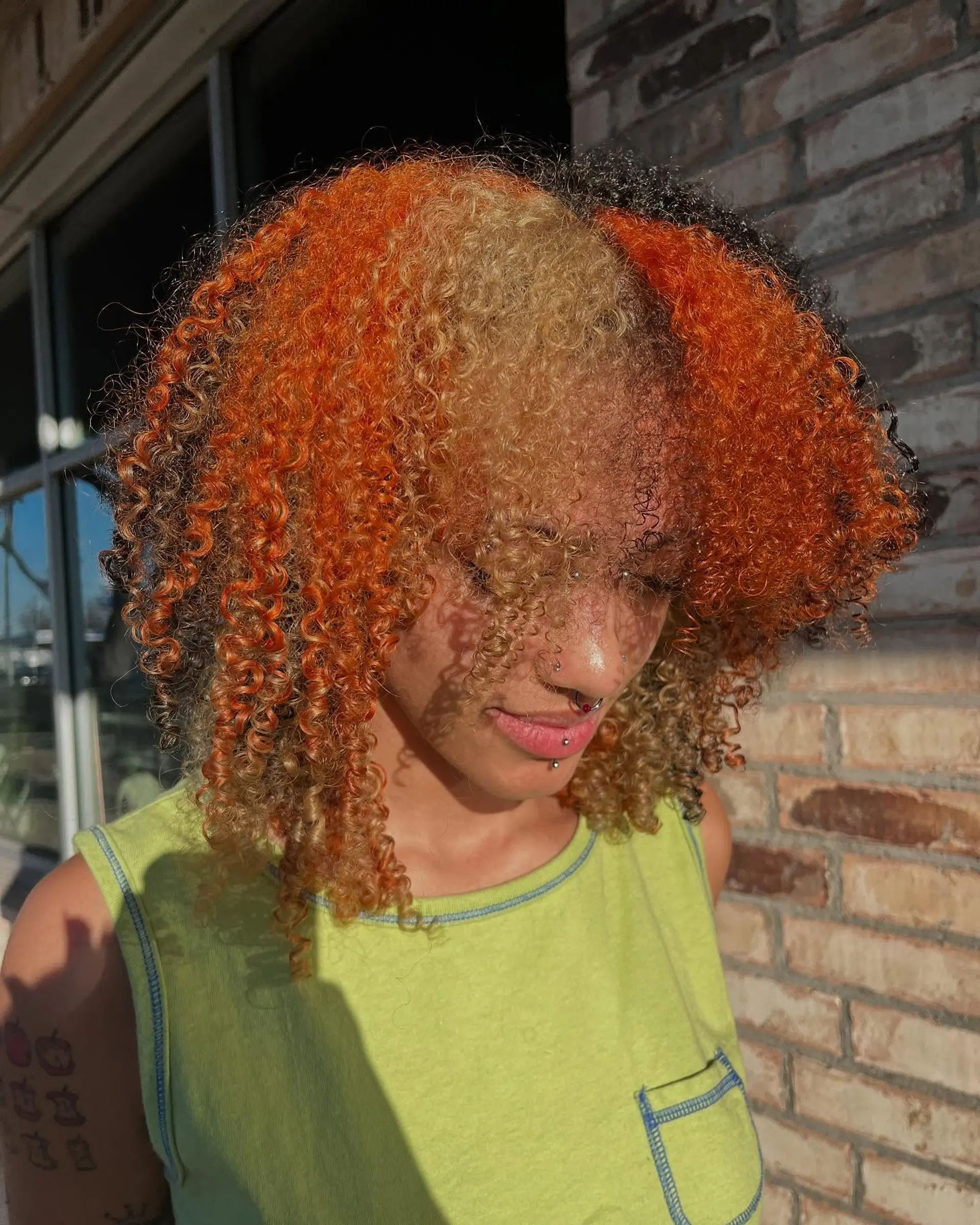 Medium-length curly hair styled with defined ringlets and a vivid calico color block pattern featuring panels of bright orange, warm blonde, and natural black. 1