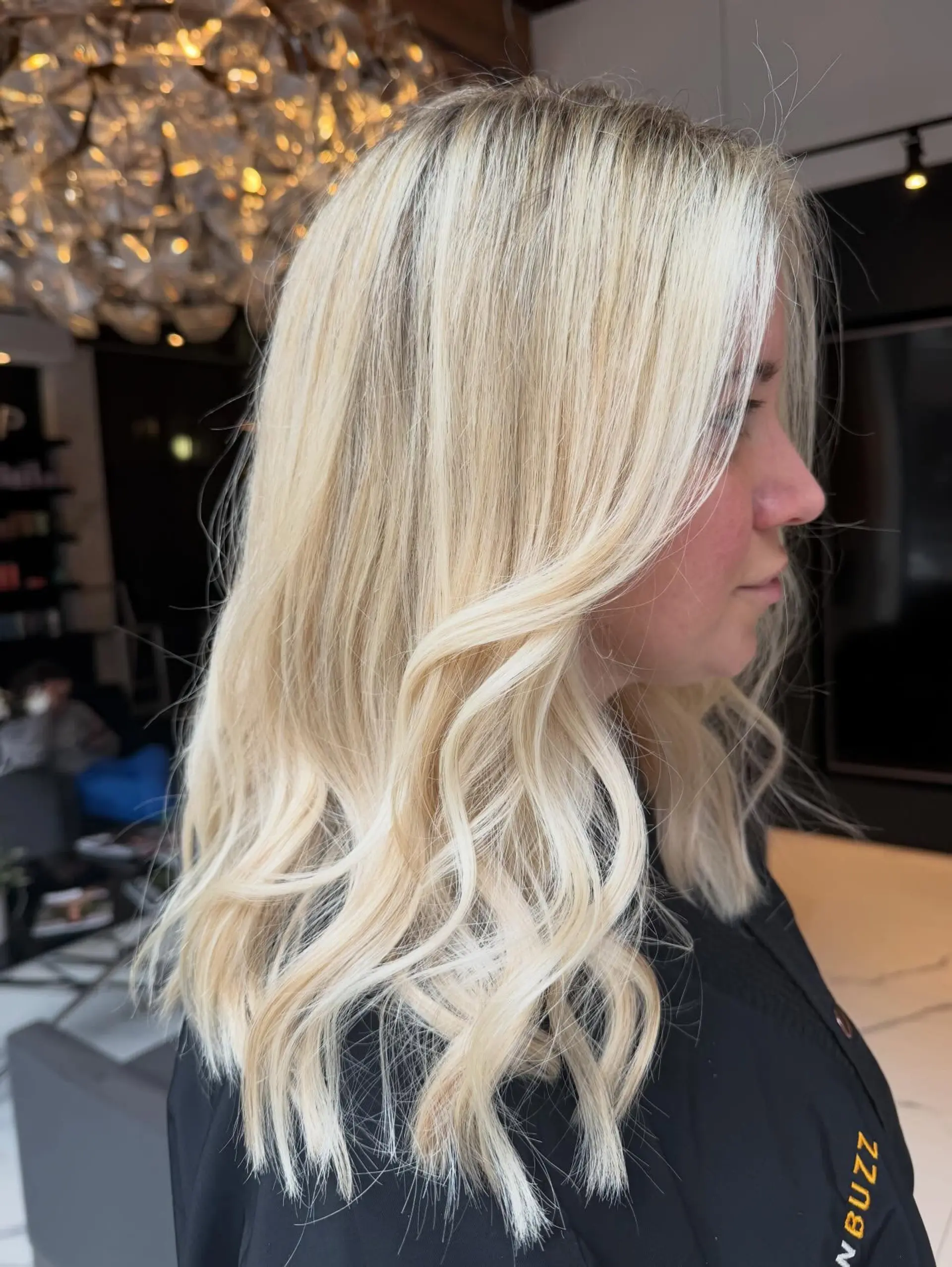 Medium-length bright blonde hair styled with soft, cascading waves and face-framing layers. 1