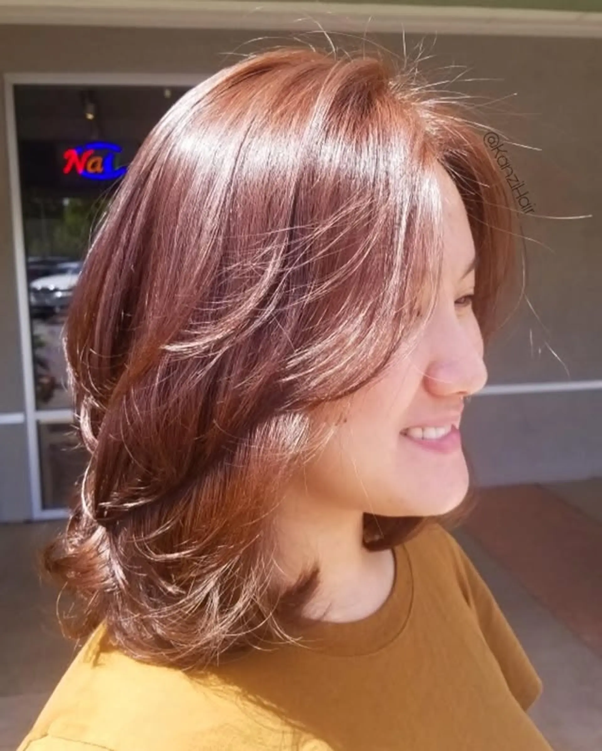 A stylish medium-length lob cut with ample layers for volume and movement. Features face-framing layers that gently sweep away from the face, creating a soft, feathered look around the jawline and neck. 1