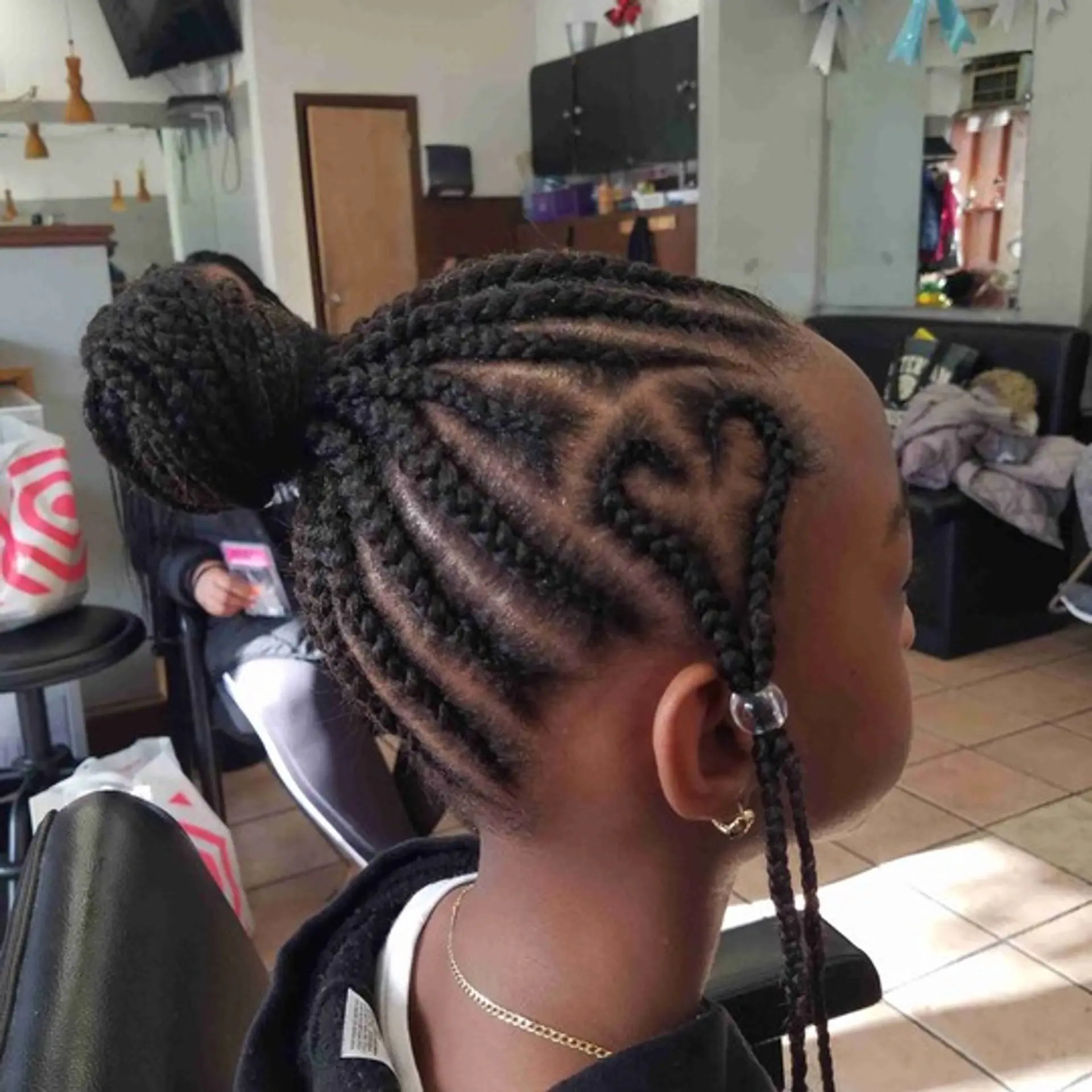 Cornrows with a braided bun and a heart design. 1