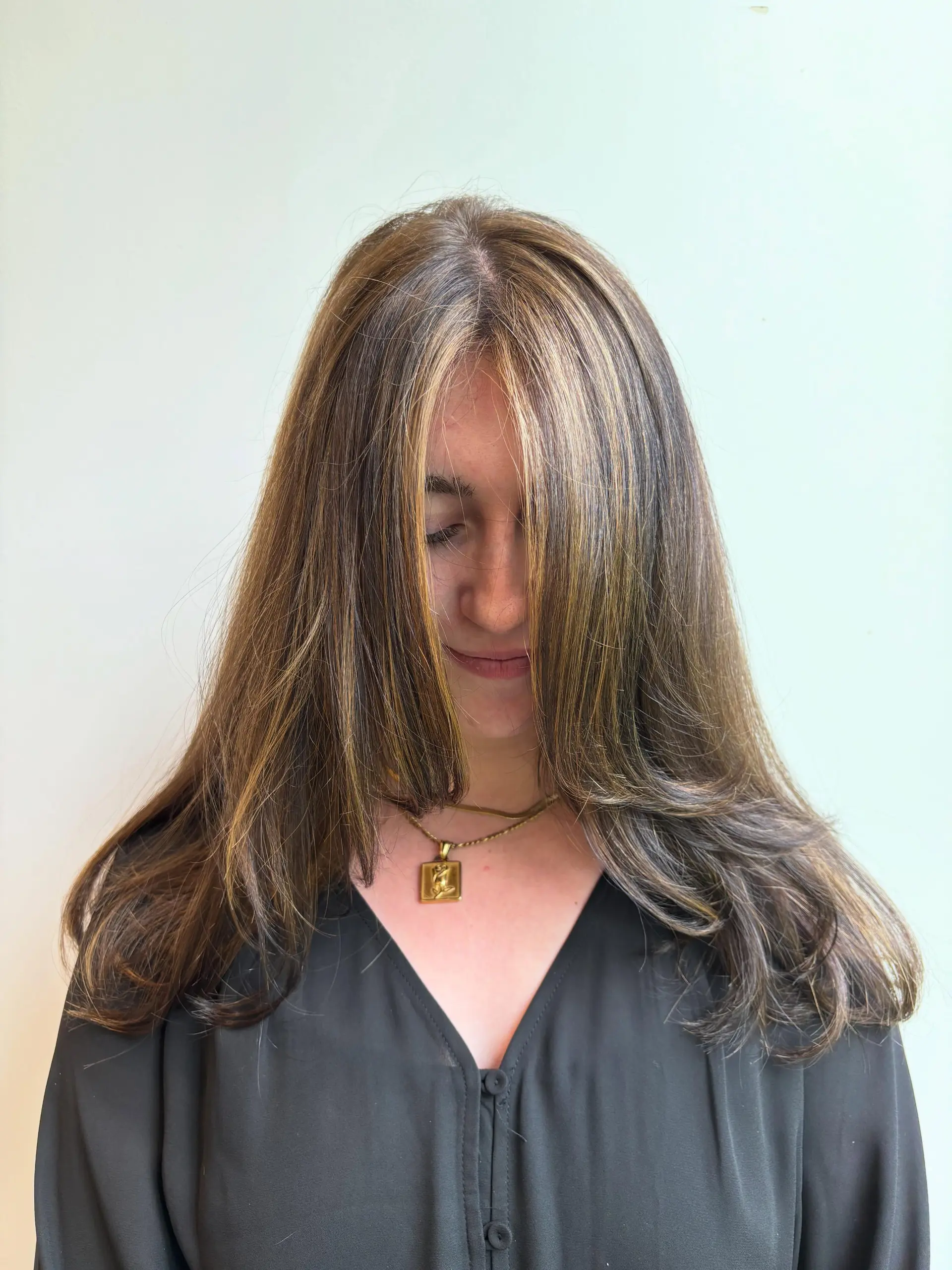 Medium-length layered haircut with seamless caramel highlights and long face-framing pieces. 1