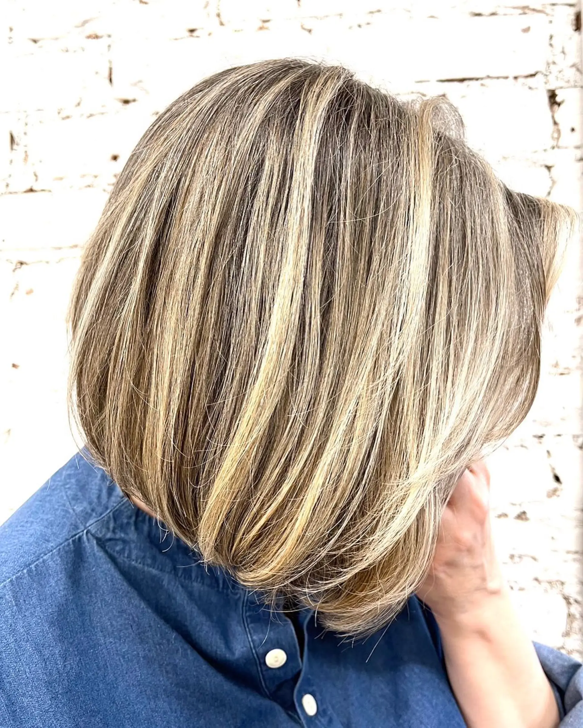 A textured chin-length bob cut enhanced with seamless, finely woven blonde balayage highlights over a natural light brown base. 1