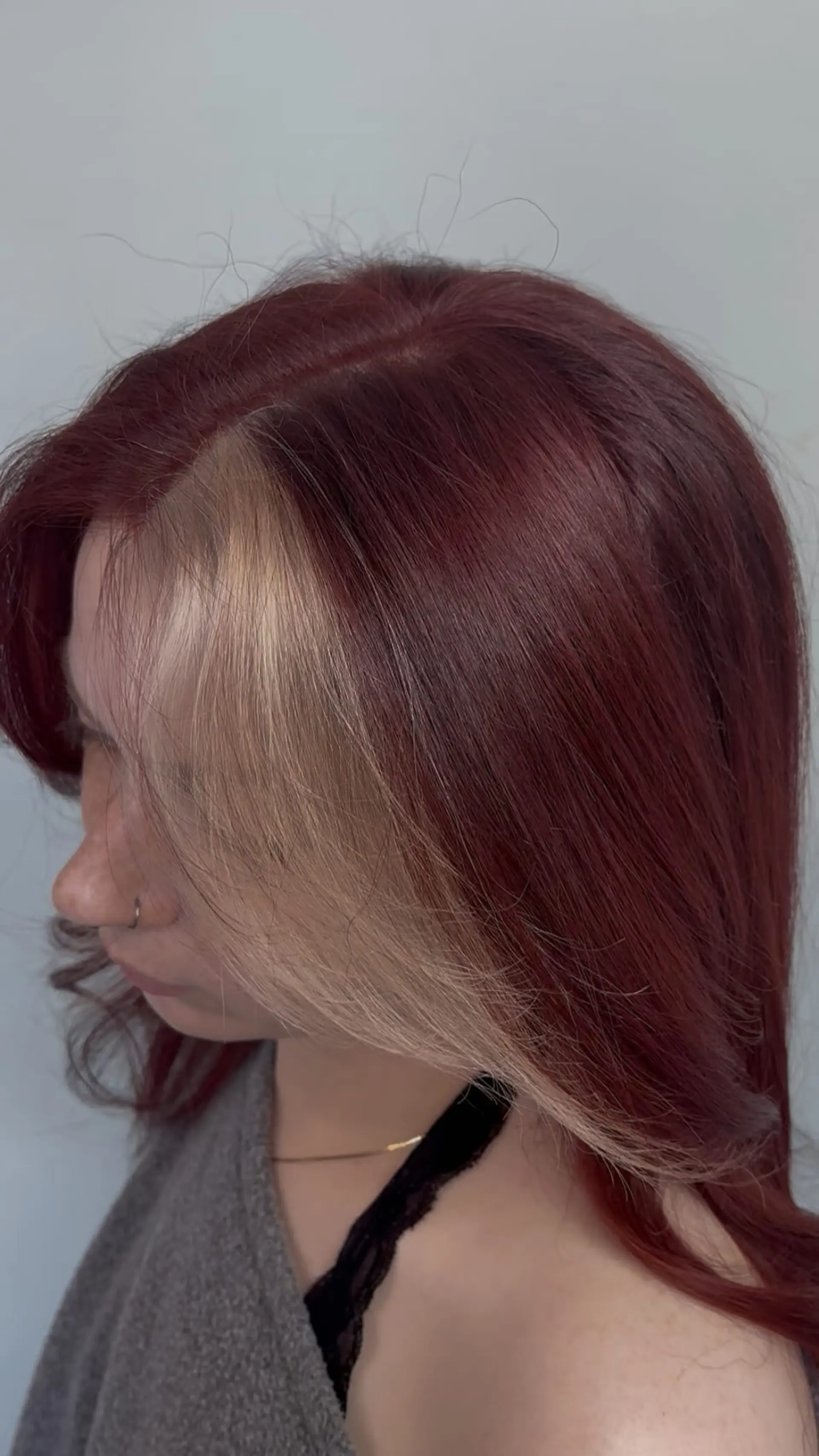 A medium-length cherry red hairstyle featuring a contrasting platinum blonde face-framing block. 1