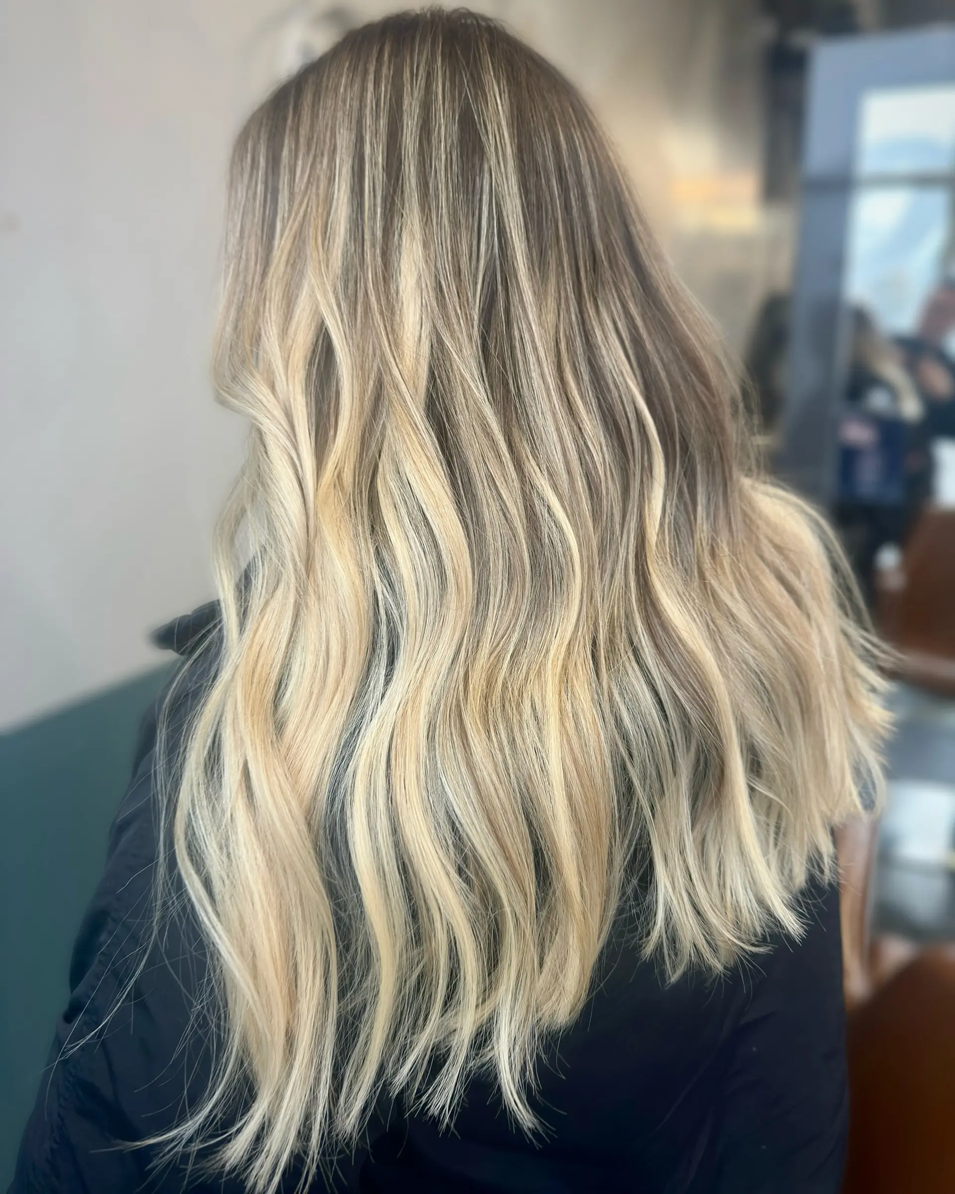 A long, wavy hairstyle with a balayage effect, blending caramel and blonde tones. 1
