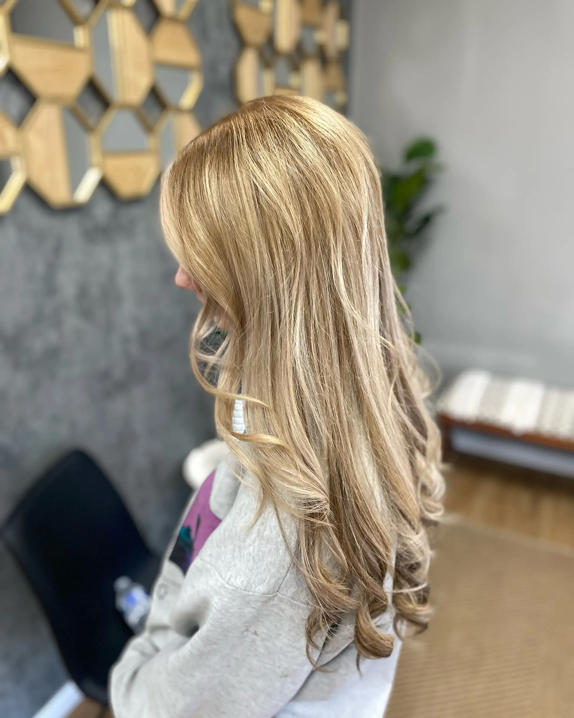 Long multi-dimensional blonde hair styled smooth with loose curls through the ends. 1