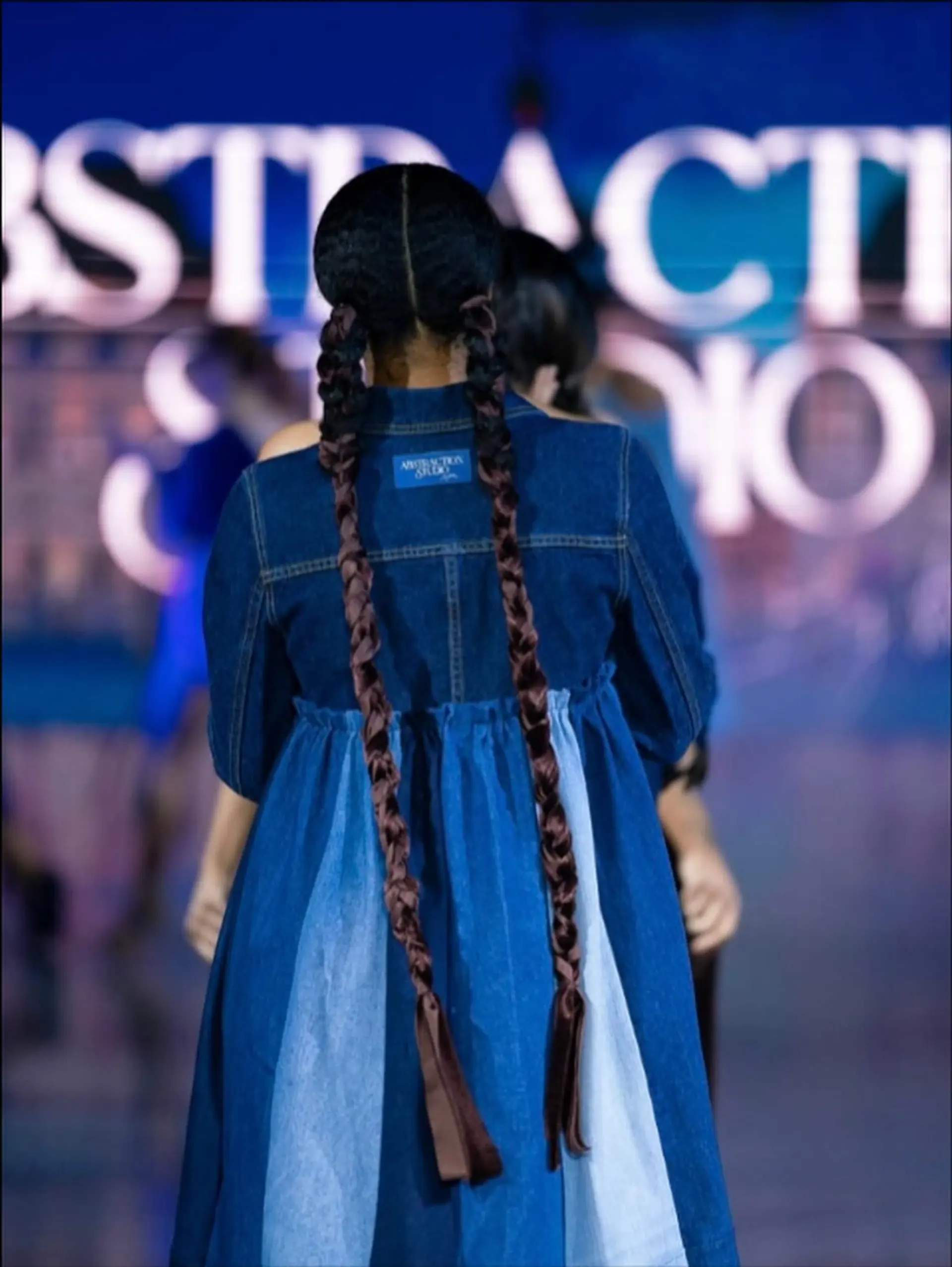 Sleek center-parted hair gathered into two ultra-long pigtail braids woven with rich brown ribbons. 1