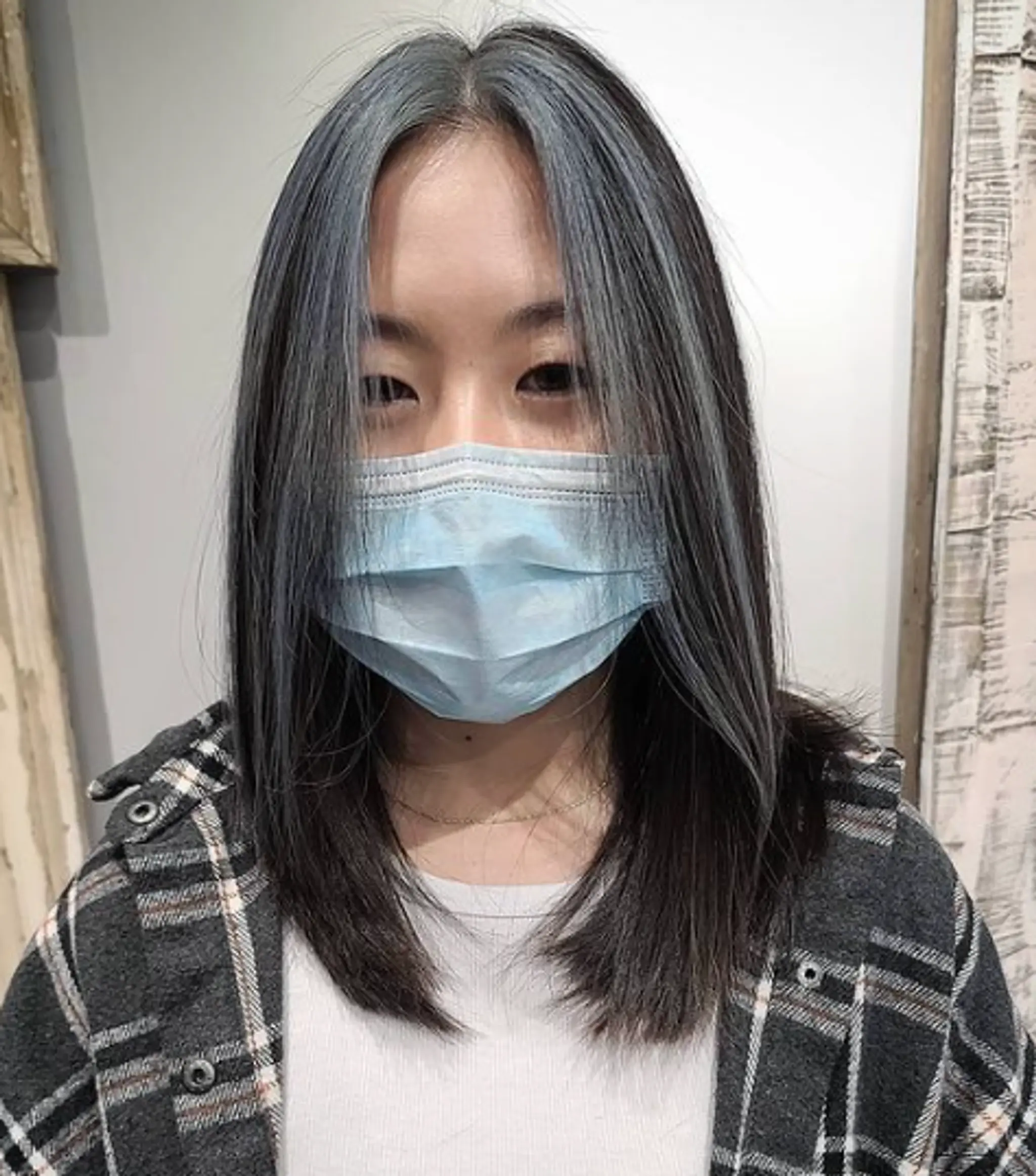 Medium-length straight hair with a middle part, featuring silver highlights with black and gray undertones, and face-framing layers.