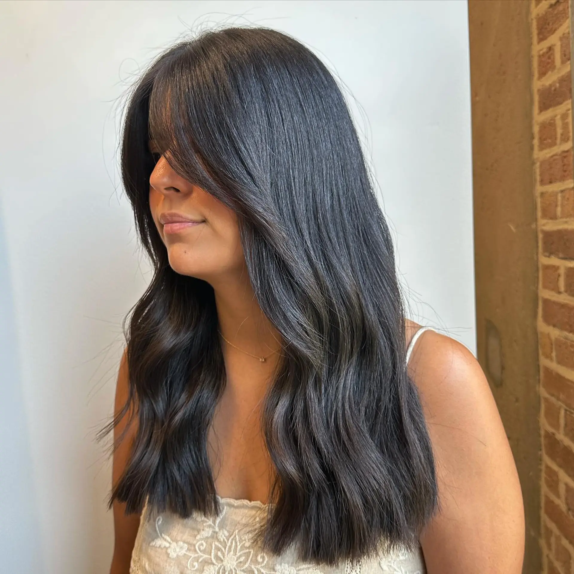 A long layered wavy hairstyle with face-framing curtain bangs. 1