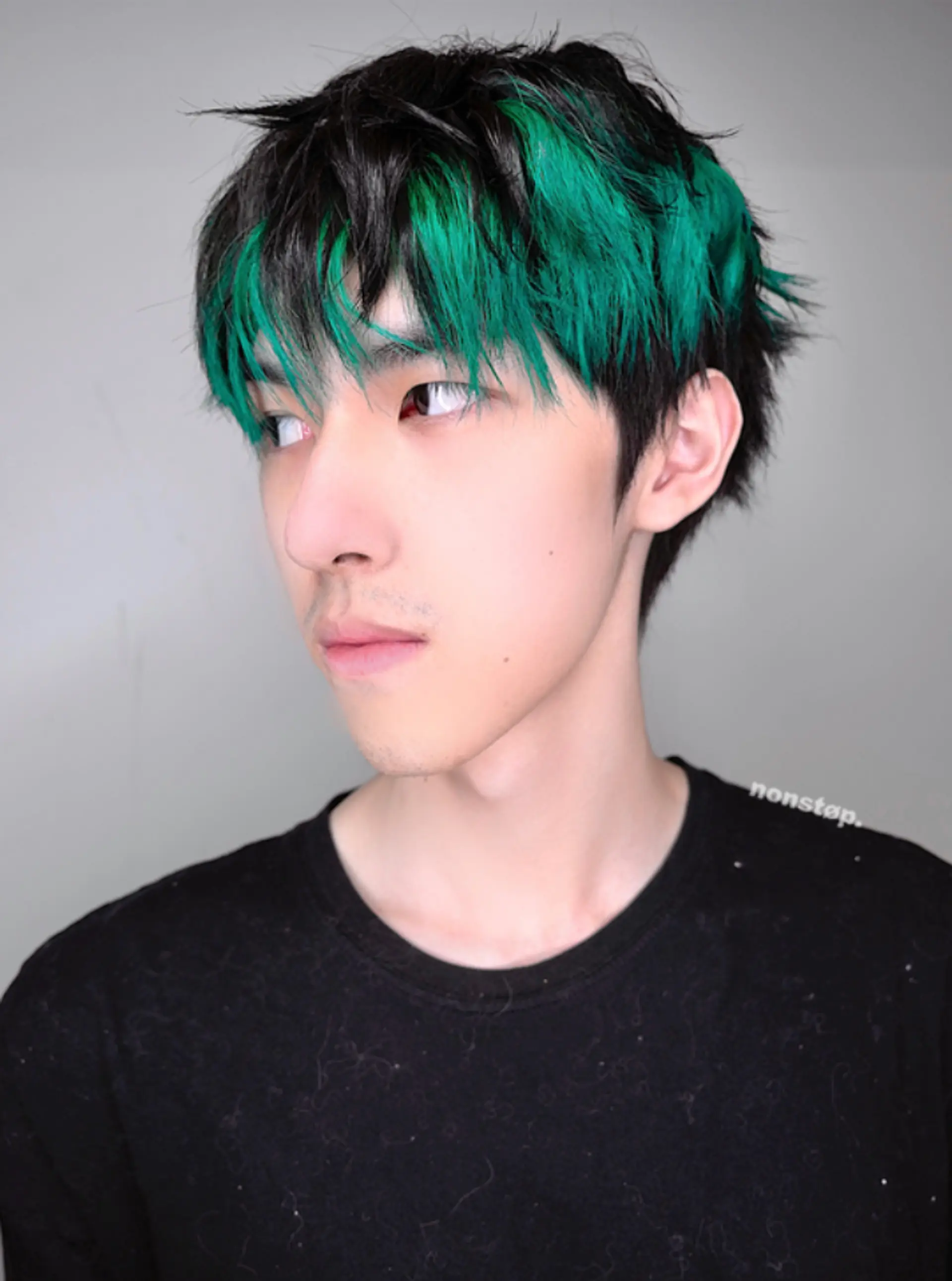 A distinctive, edgy hairstyle featuring a vibrant green fringe contrasted with natural black at the roots. The hair is short, layered, and textured, giving it a tousled appearance with a jagged, choppy fringe. 1