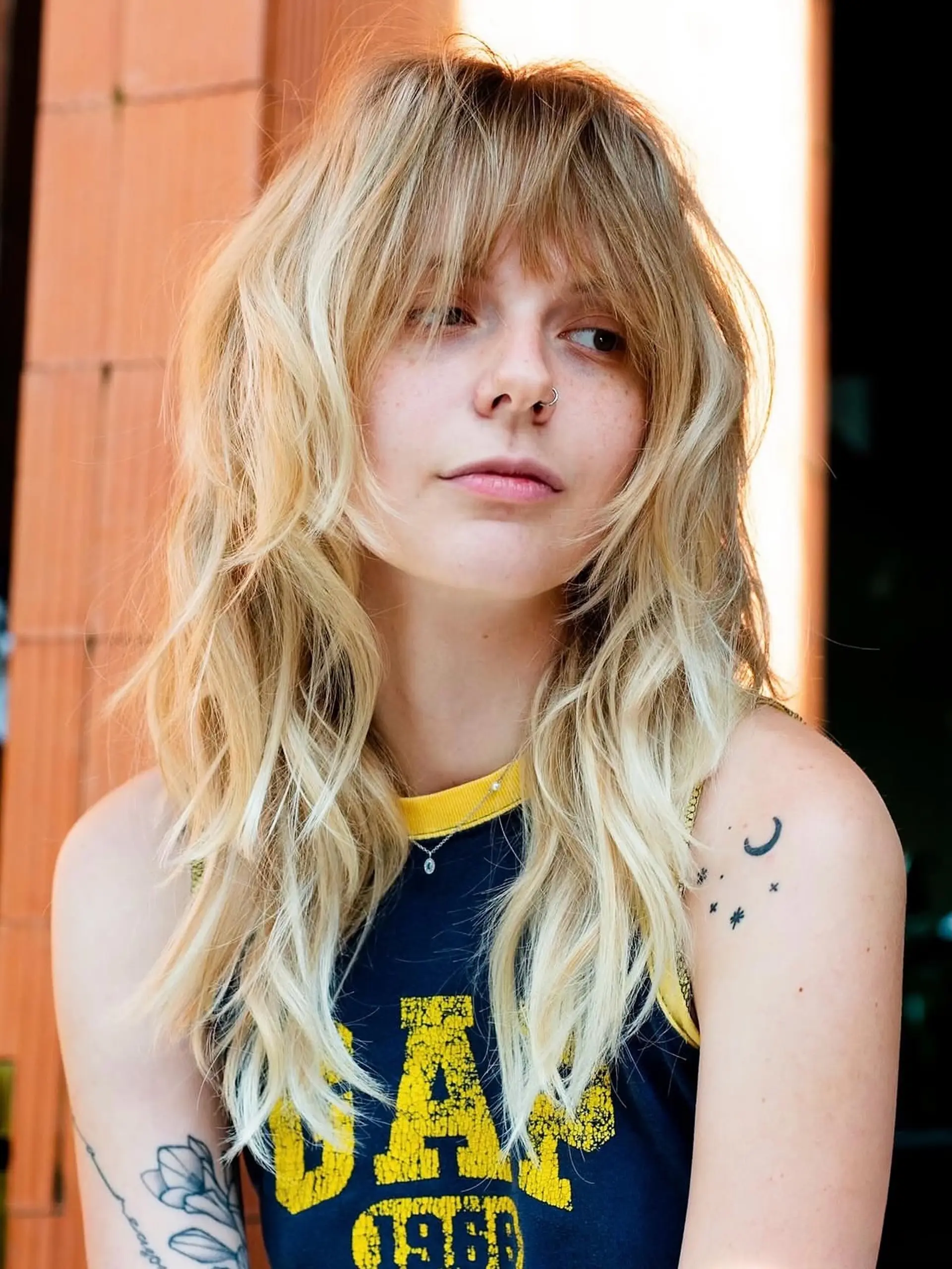 A medium-length textured shag haircut featuring full, piecey fringe and cascading face-framing layers with soft, tousled waves. 1