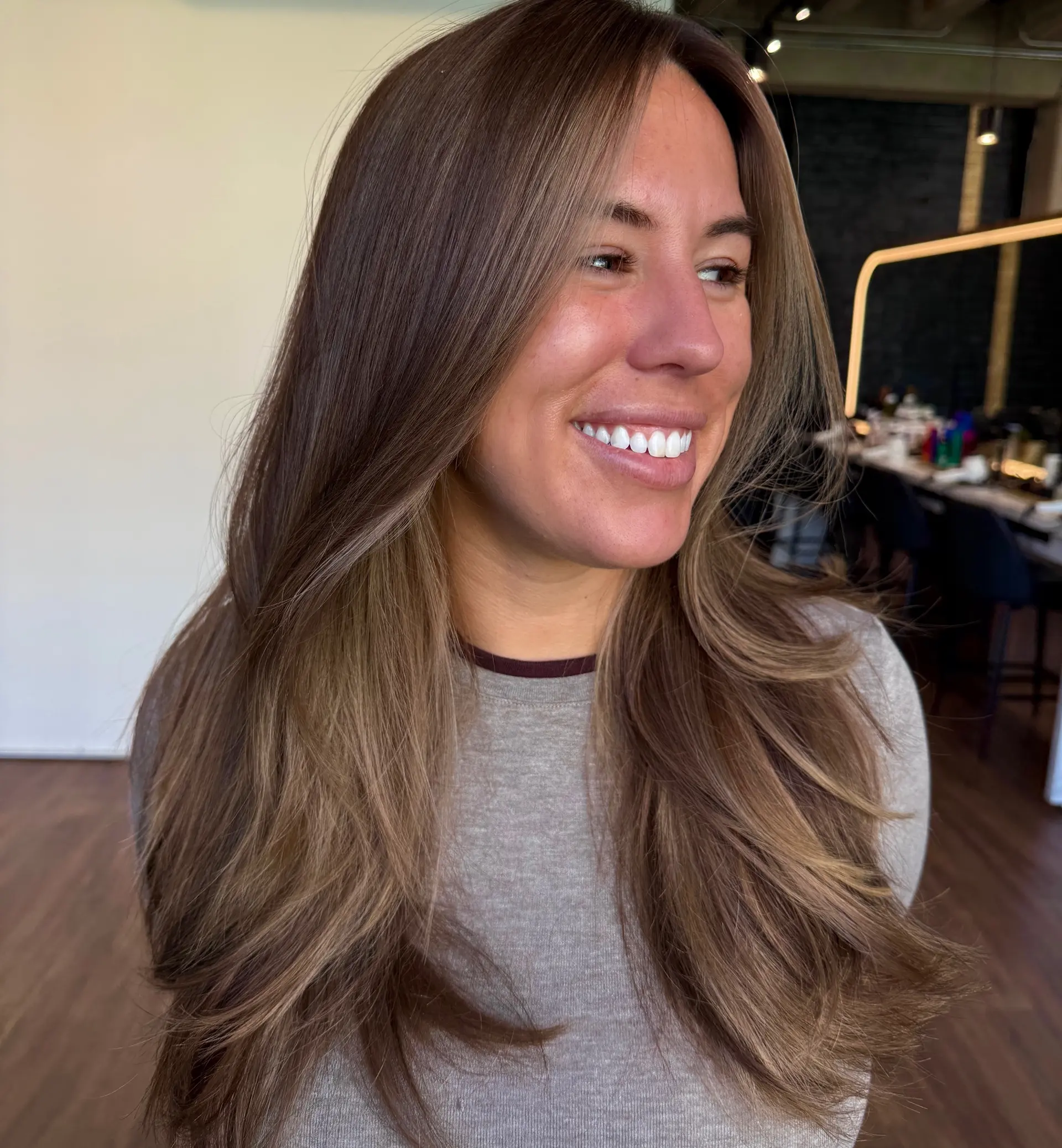 Long dimensional brunette hair styled in a voluminous blowout with soft face-framing layers. 1