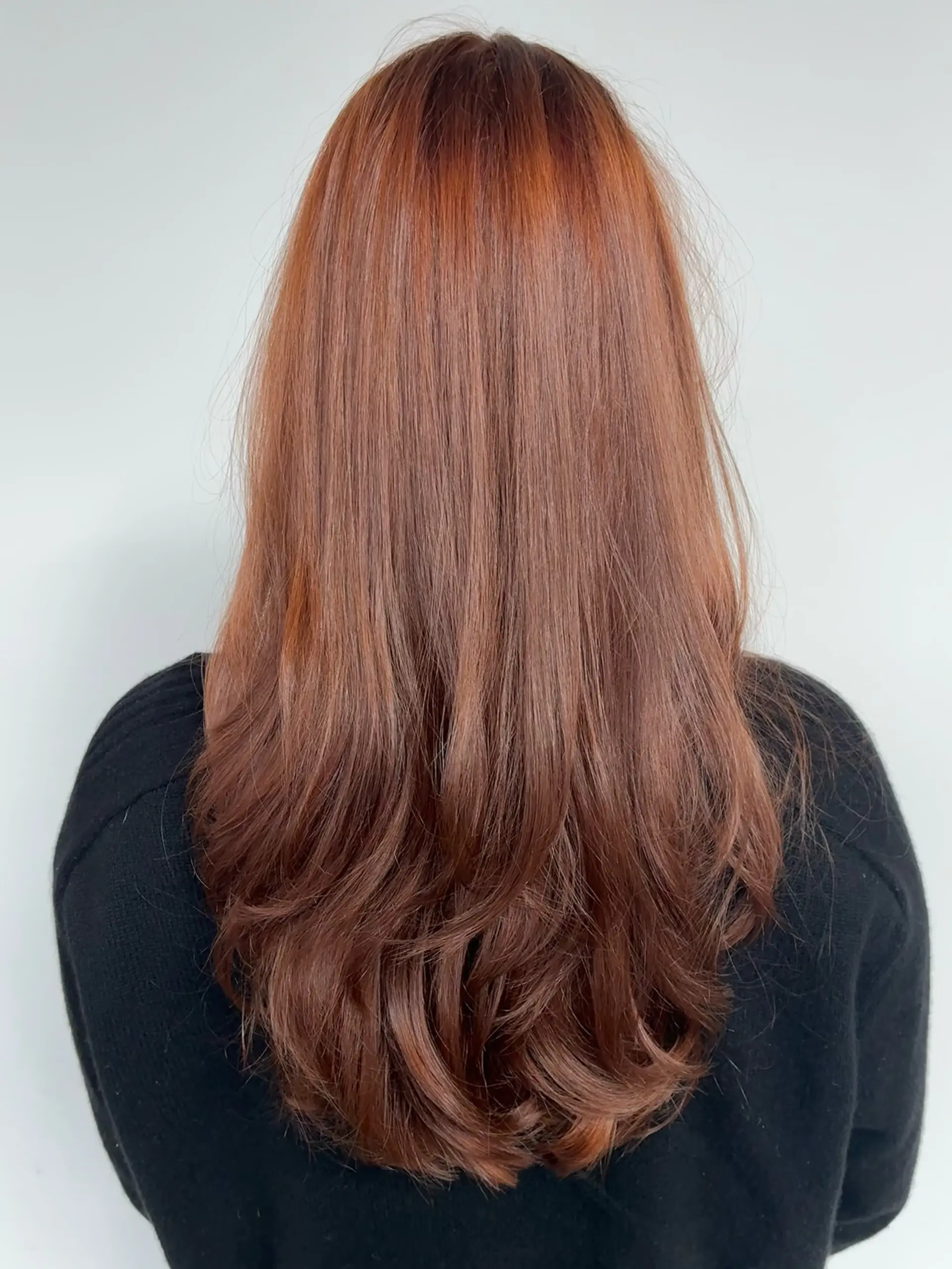 Long deep copper hair styled with cascading layers and soft, curled ends. 1