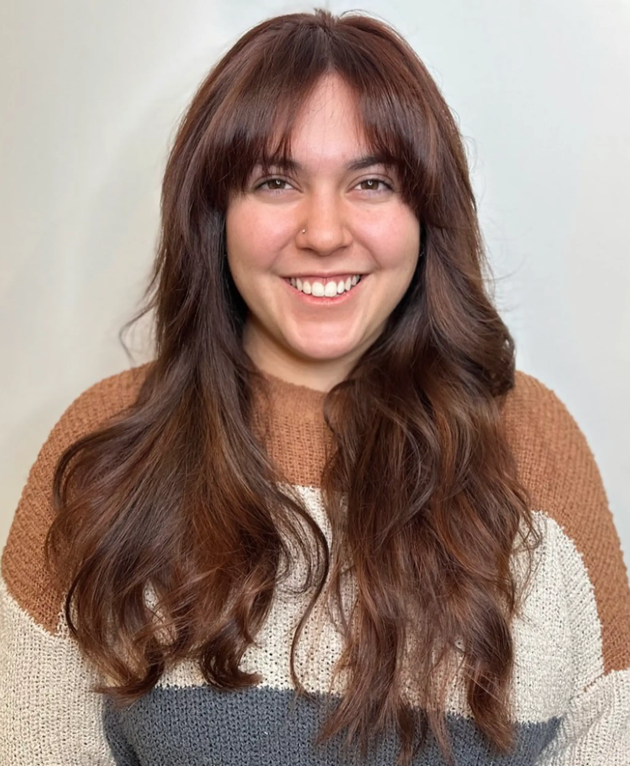 Long natural chestnut brown waves with subtle layers and a wispy fringe.

Color by @simabeautynyc