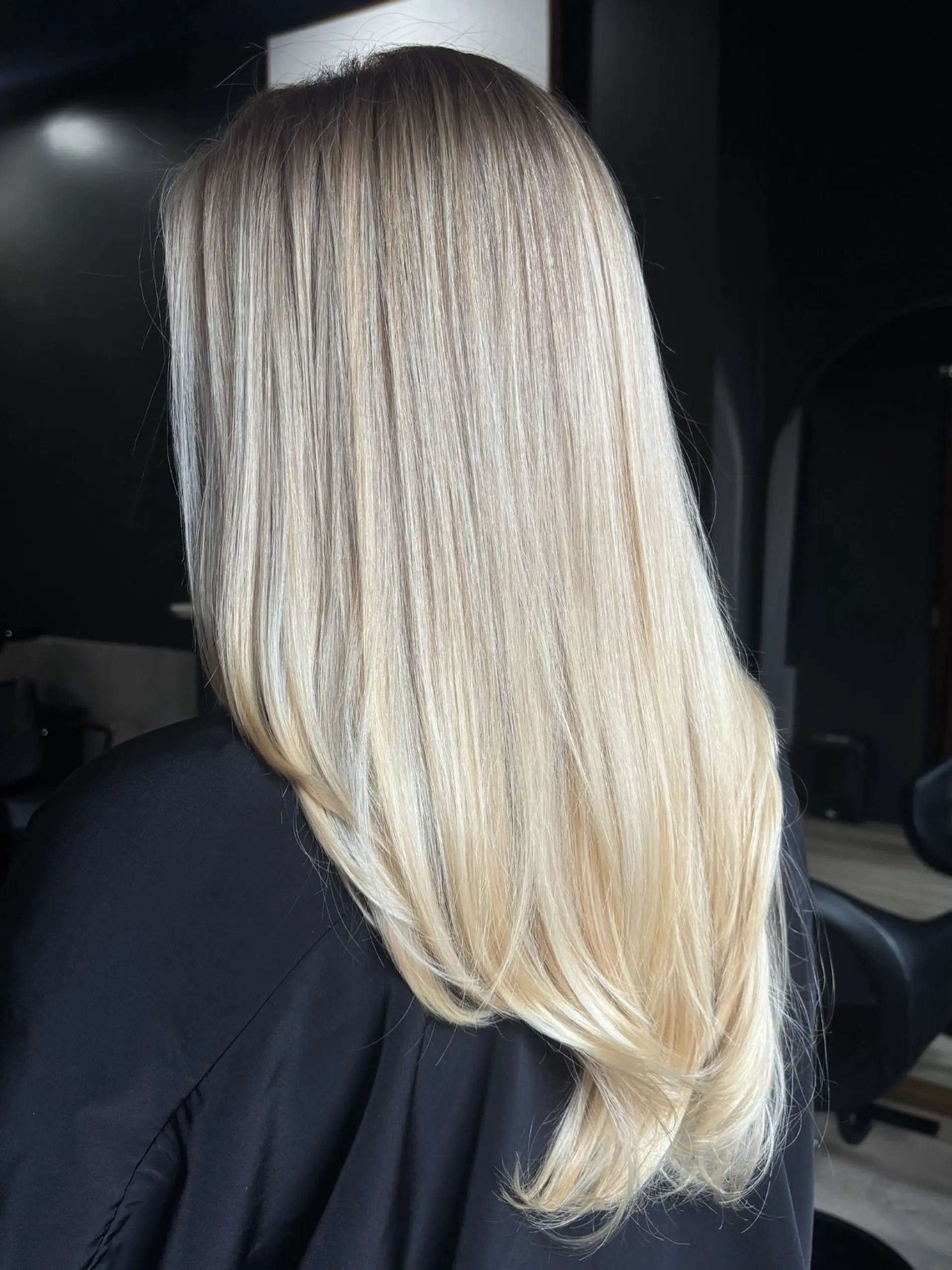 Long, sleek butter blonde hair with natural lived-in roots and multi-dimensional tones. 1