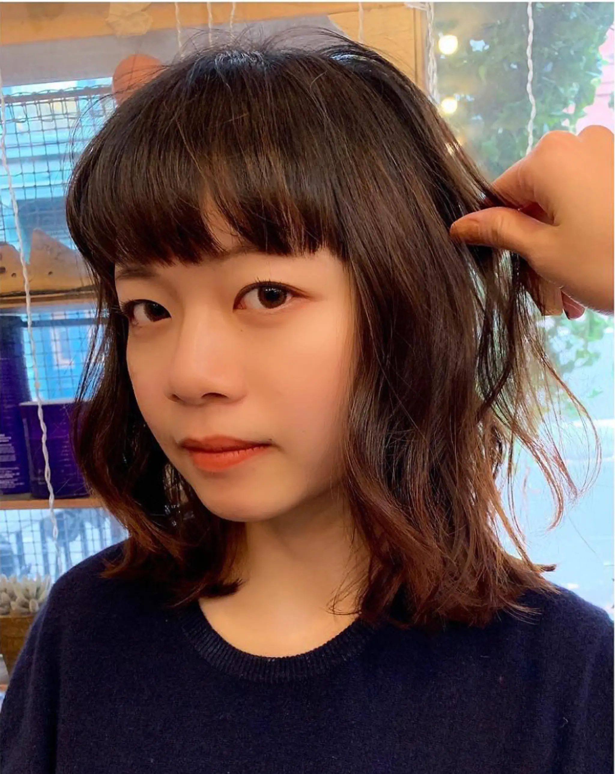Medium-length wavy bob with dark brown base and light brown highlights, complete with full bangs by Emma.