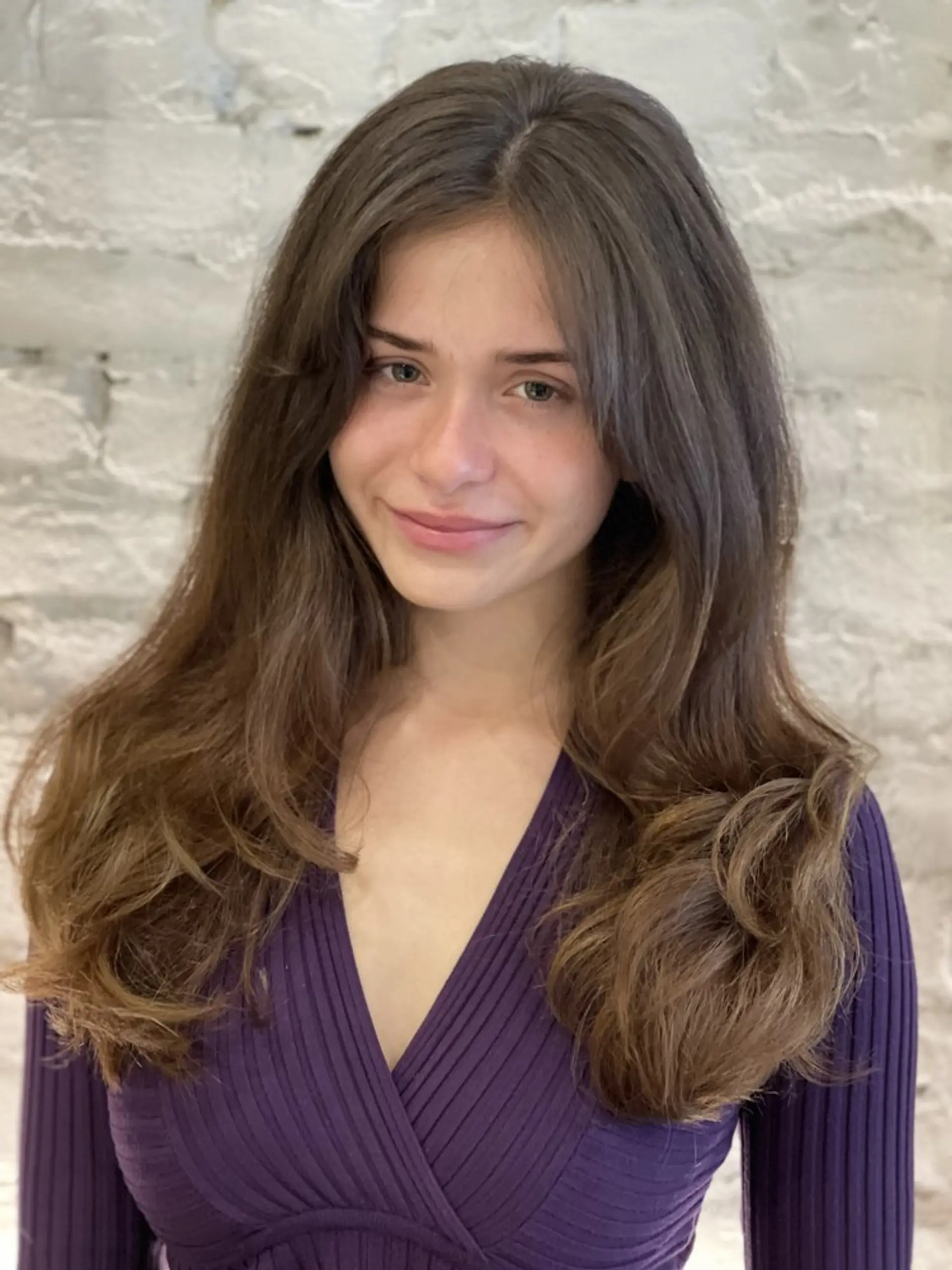 A layered long hairstyle with soft waves and face-framing curtain bangs. 1