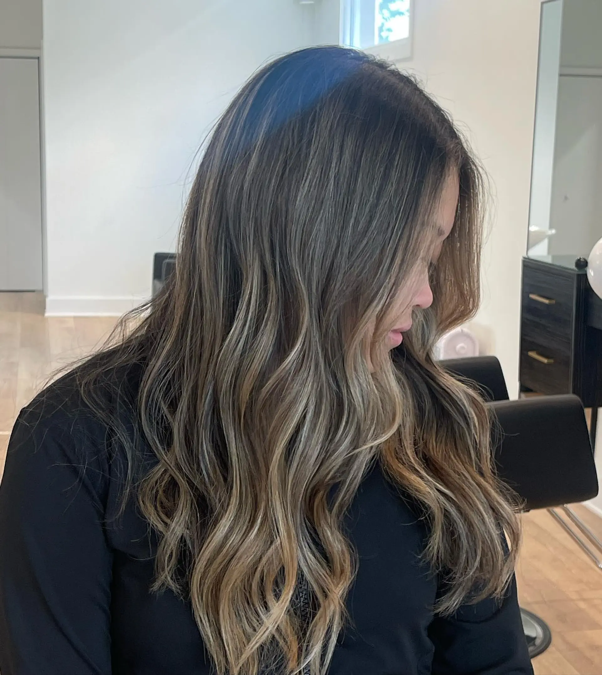 Long dimensional brunette hair styled in soft, effortless waves with seamlessly blended balayage highlights. 1