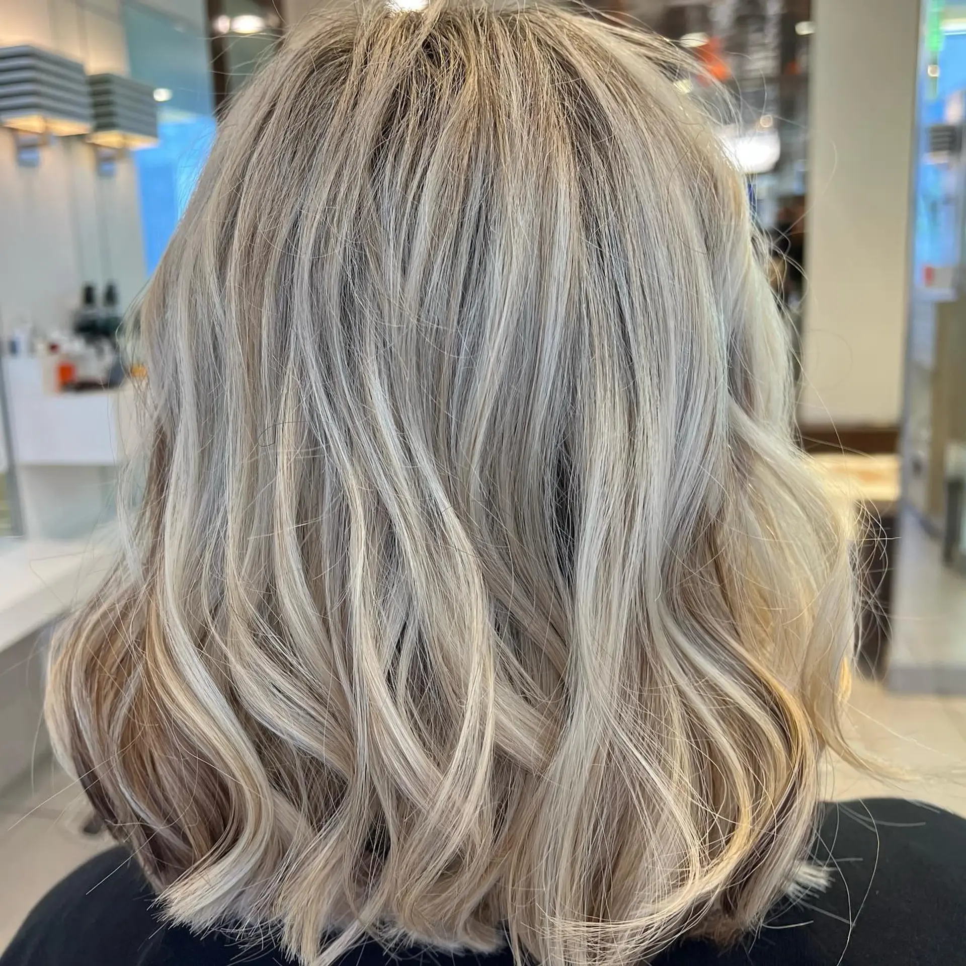 A textured medium-length lob styled with loose, dimensional cool blonde waves. 1