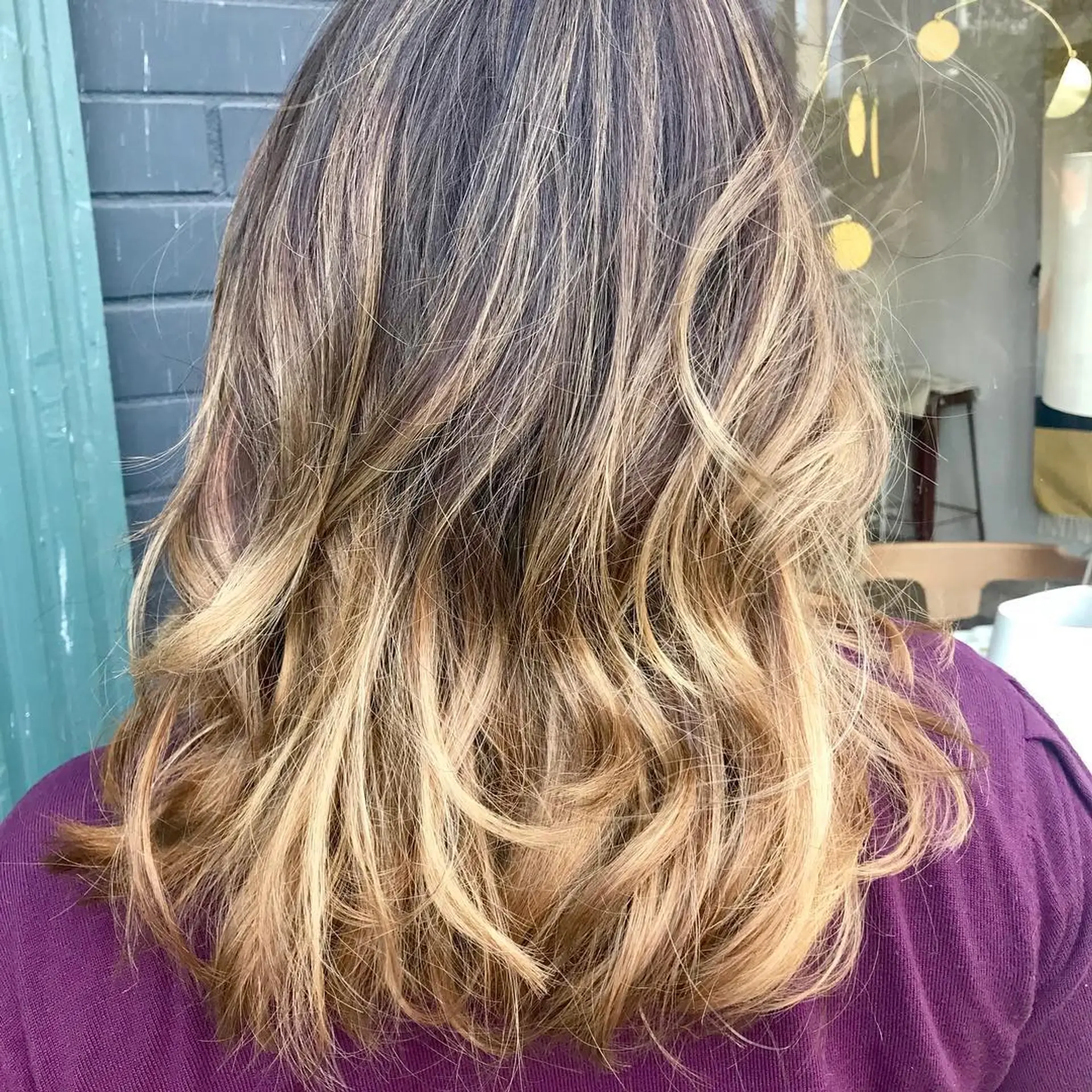 Medium-length layered cut styled with textured waves and seamless golden blonde balayage highlights. 1