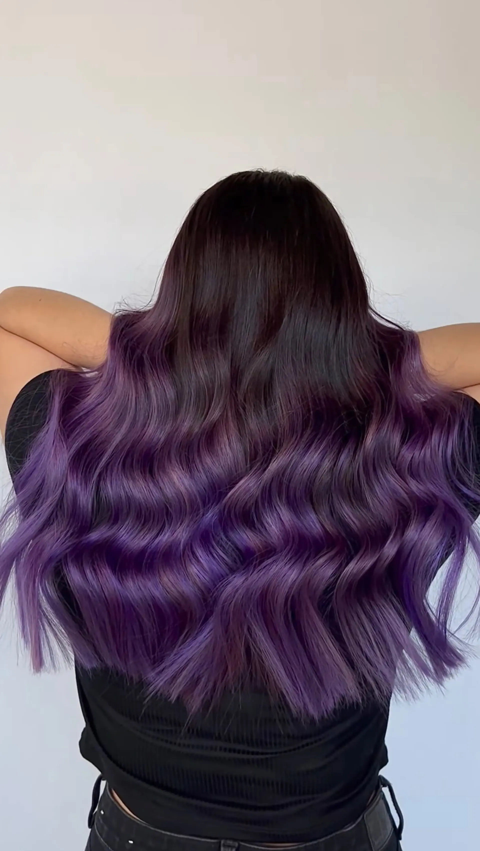 Long dark hair transitioning into a rich violet and purple balayage, styled with cascading glossy waves. 1