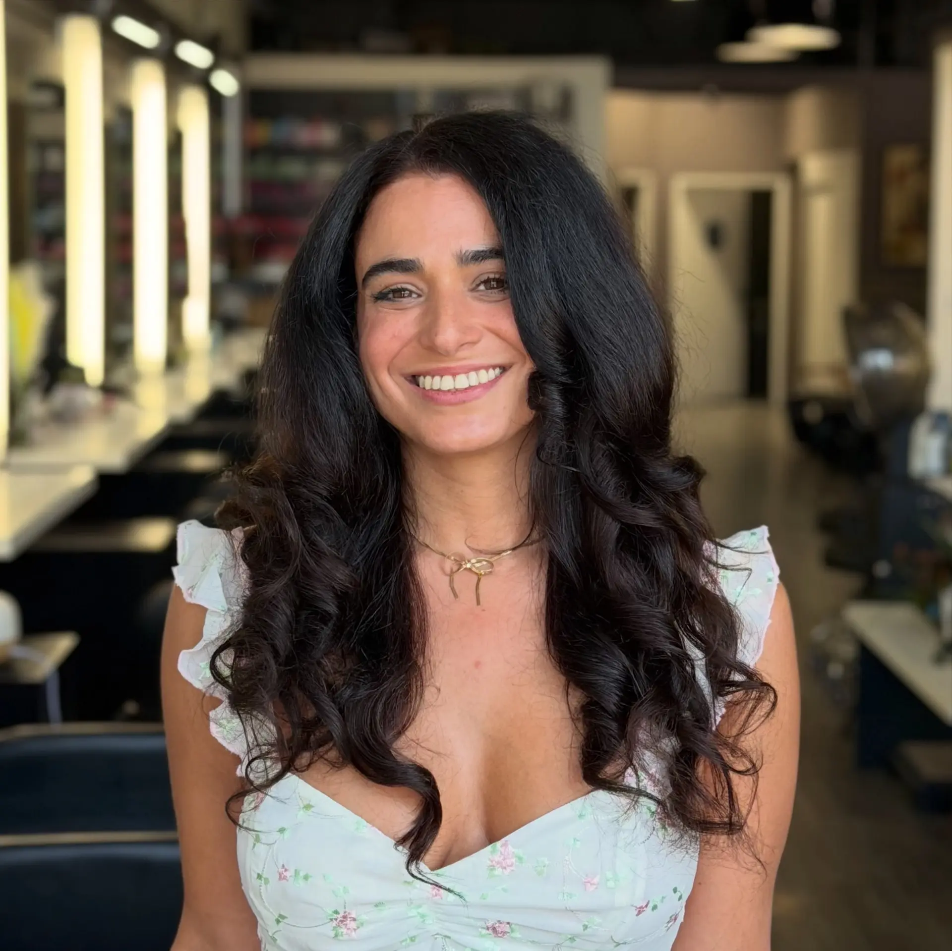 Long, rich dark brunette hair styled in a bouncy, voluminous blowout with soft spiral waves framing the shoulders. 1