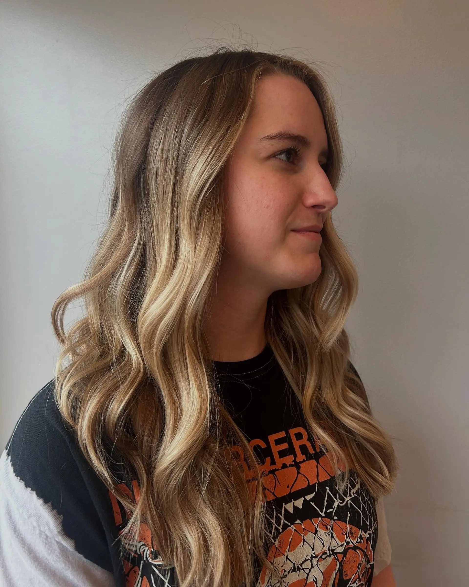 Long hair featuring a seamless blonde balayage with face-framing highlights, styled into soft beachy waves. 1