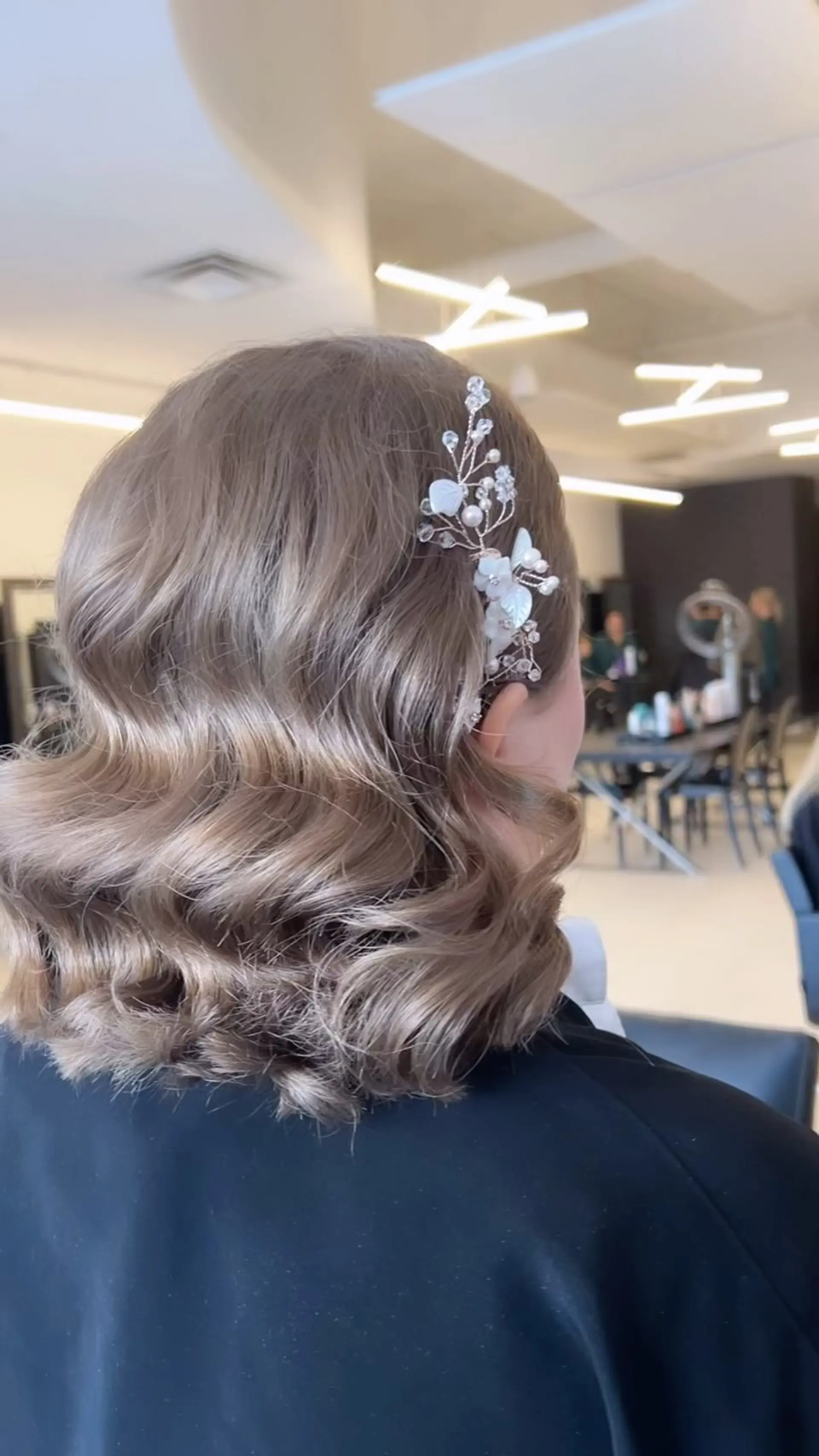 Polished shoulder-length Hollywood waves styled with a delicate pearl and crystal floral hairpin. 1