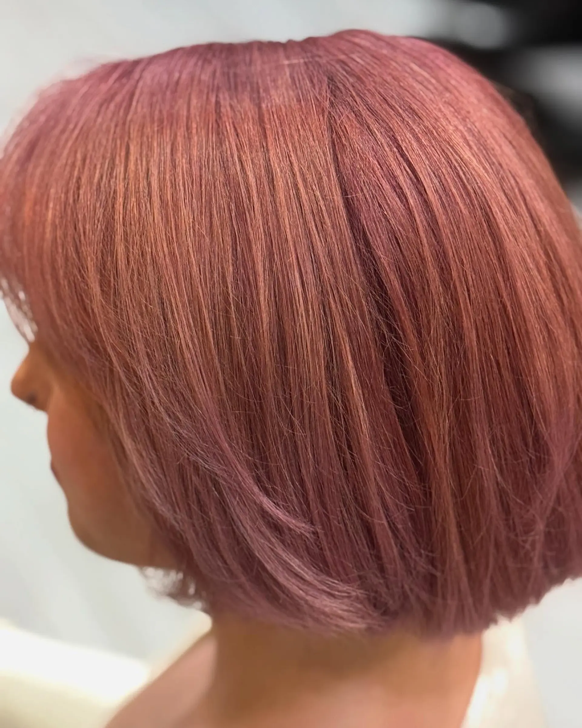 A sleek, chin-length bob colored in a soft dusty rose pink with gently beveled ends. 1
