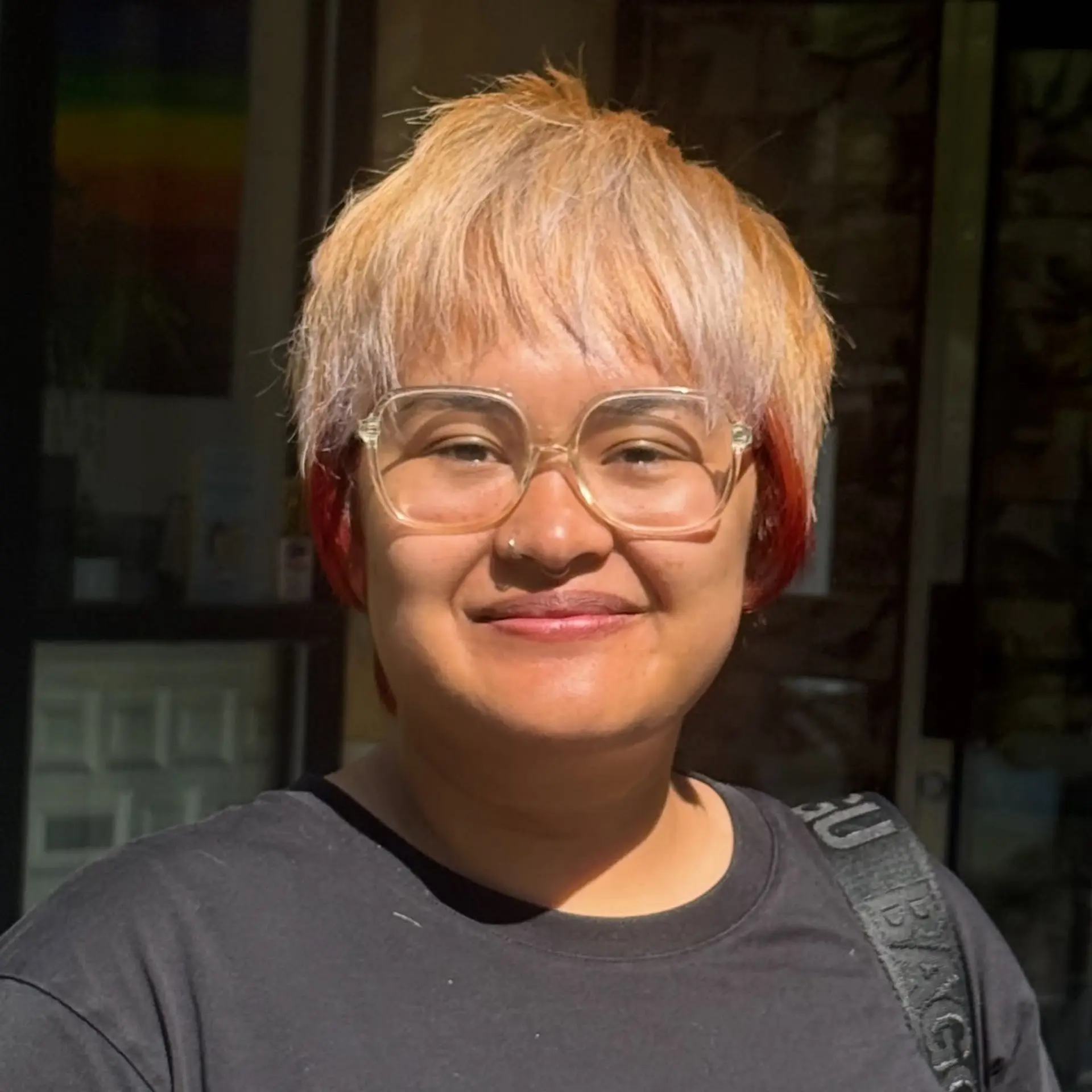 A textured short crop pixie cut with fringe, combining light blonde and pastel tones with contrasting red accents on the sides. 1