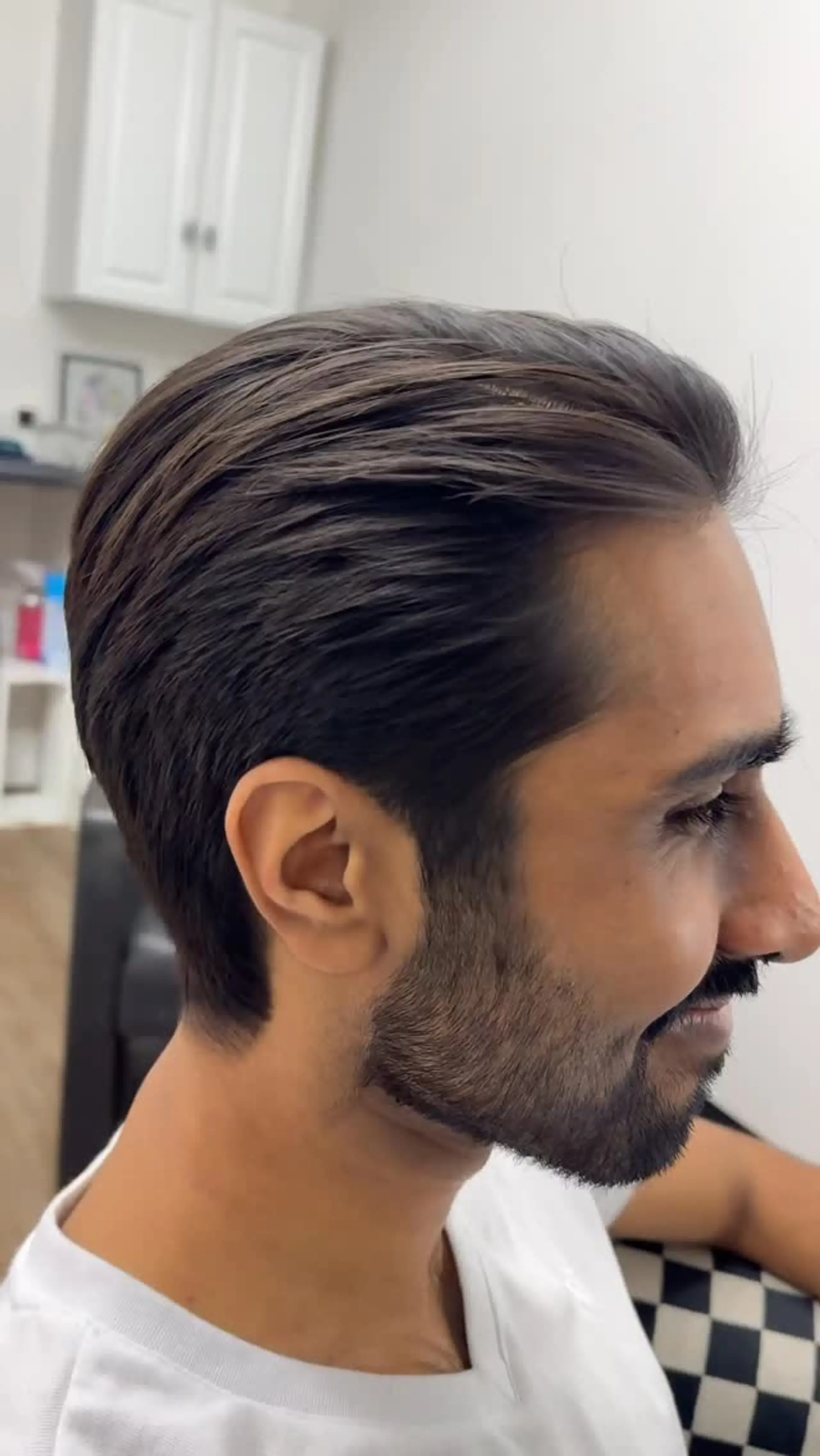 A textured swept-back hairstyle with neatly tapered sides and a groomed beard. 1